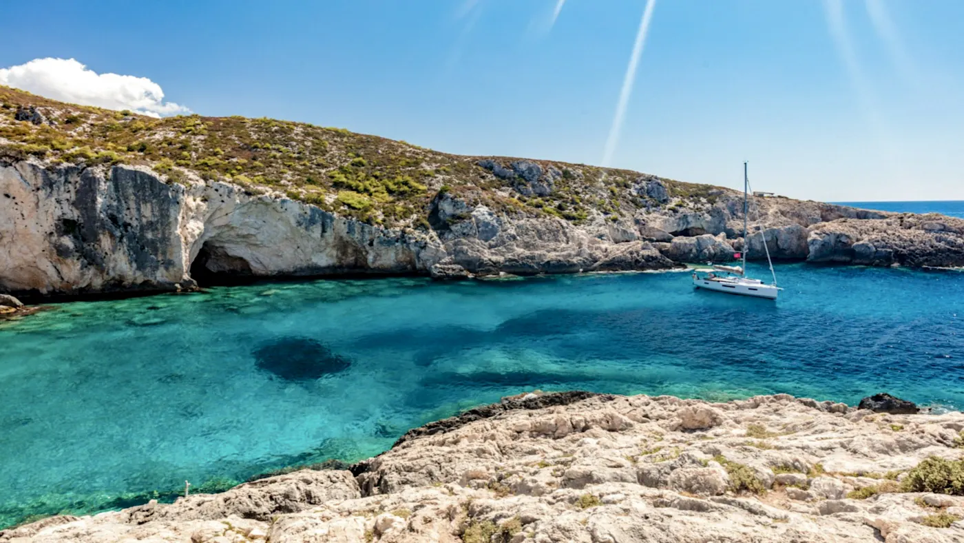 Griechenland,Zakynthos, Limnionas, Segelboot Segelboot im türkisfarbenen Wasser vor Felsen und Höhle, Limnionas, Zakynthos, Griechenland.