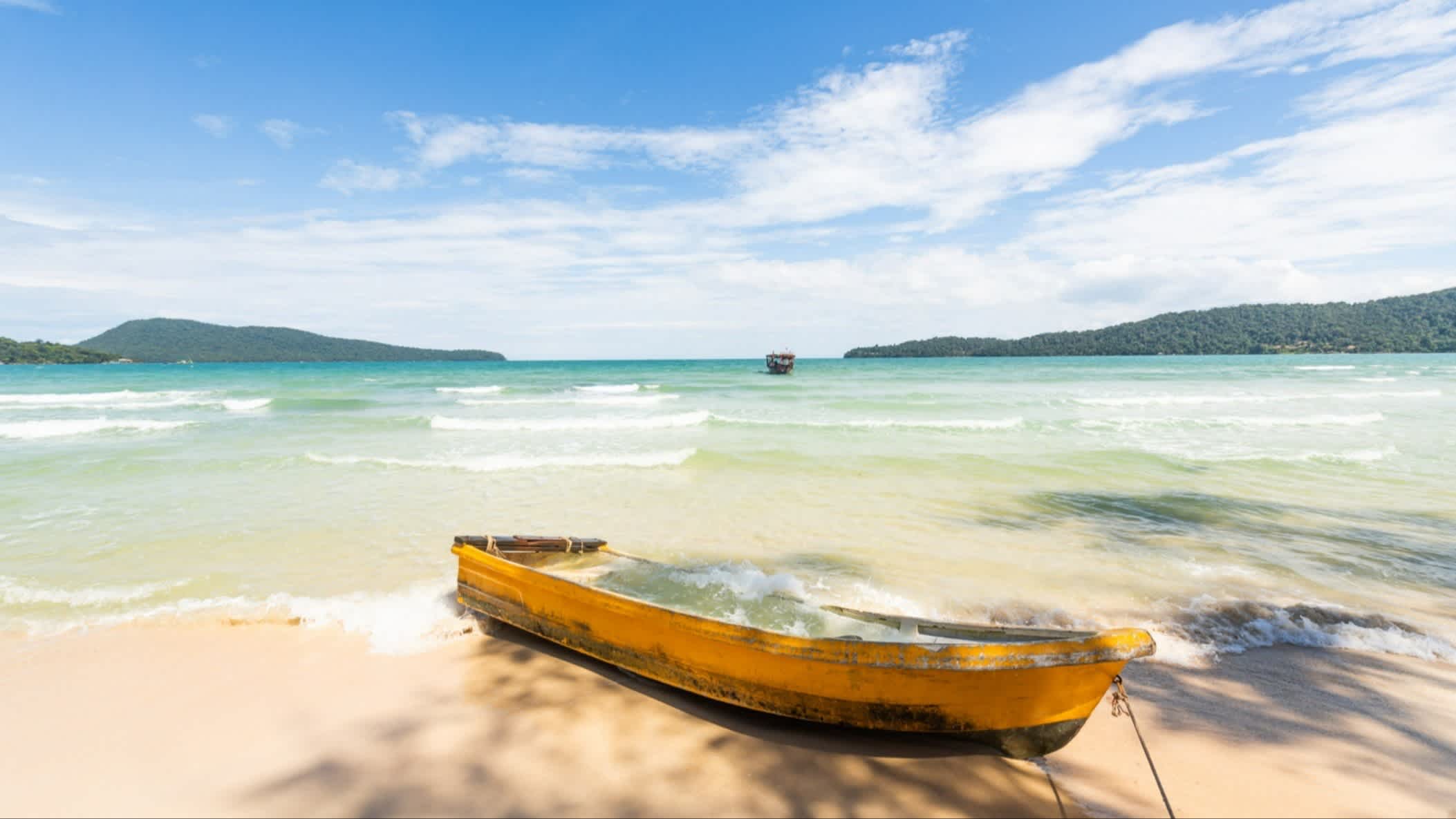 Gelbes Boot am Strand von Koh Tonsay, Kambodscha bei seichten Wellen und blauem Himmel.