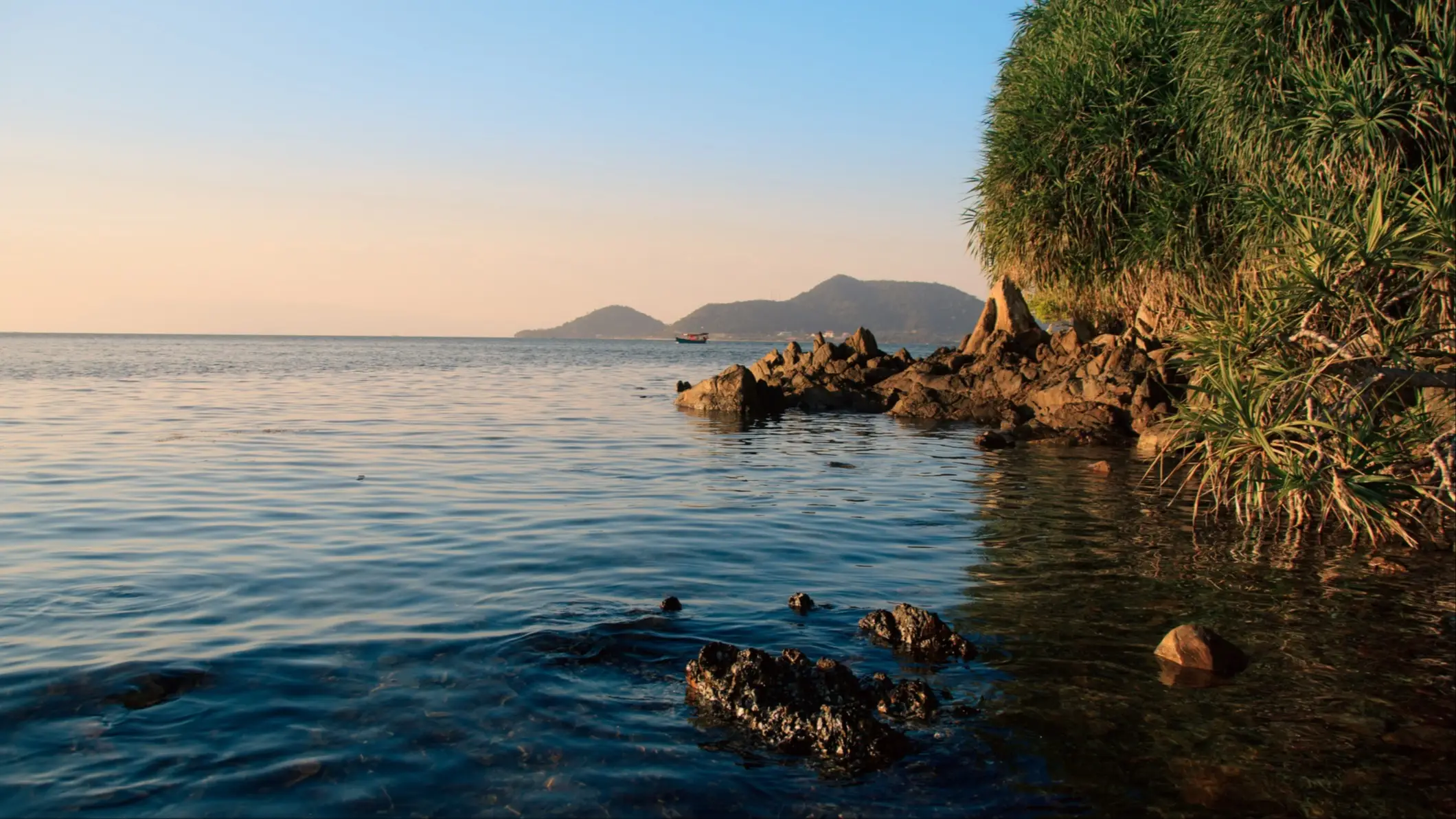 Koh Tonsai, Kep, Kambodscha Sonnenuntergang an der Küste des Koh Tonsai Strandes in Kep, Kambodscha bei Dämmerung und mit Blick auf die farbenfrohe Vegetation und Felsen.