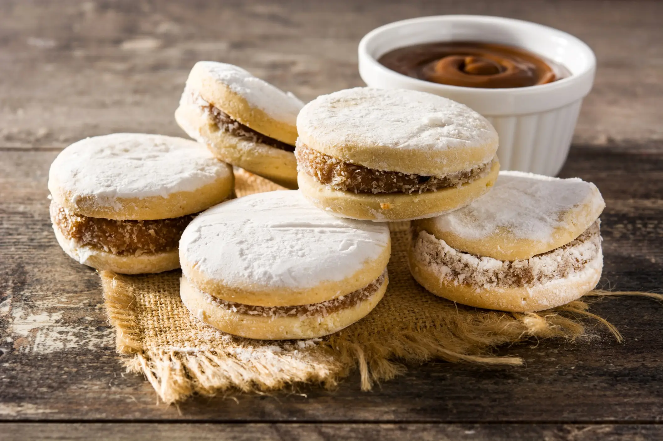Argentinien, Alfajores Traditionelle argentinische Alfajores mit Dulce de Leche und Zucker auf Holztisch.