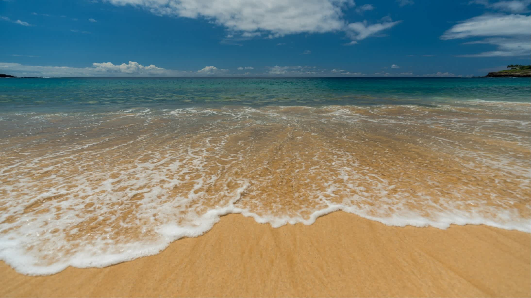 Der Strand auf Lanai, Hawaii, USA bei Sonnenschein und mit Blick auf das Meer und den goldenen Sand.