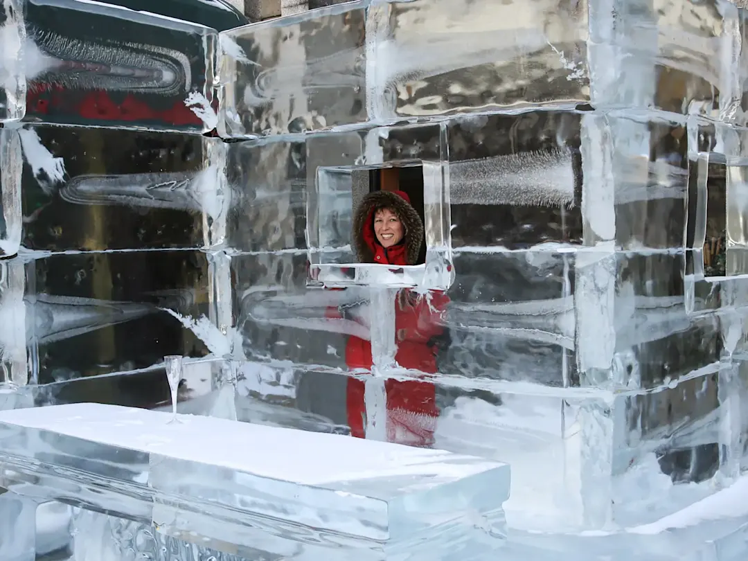 Frau in einem Hotel aus Eis mit Glas auf dem Tisch. Kirkenes, Finnmark, Norwegen.