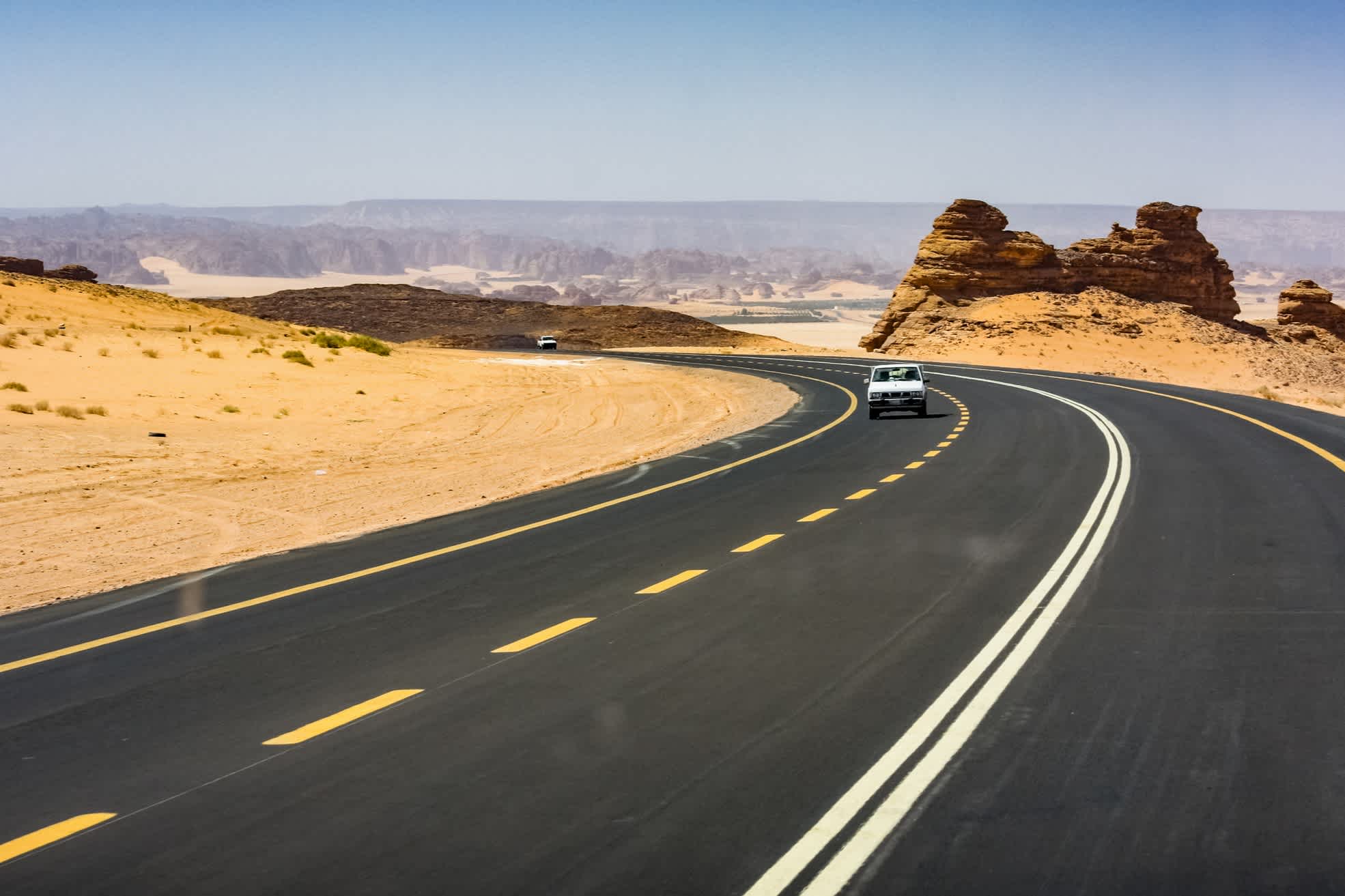 Straße durch die Wüste und ein kleines weißes Auto