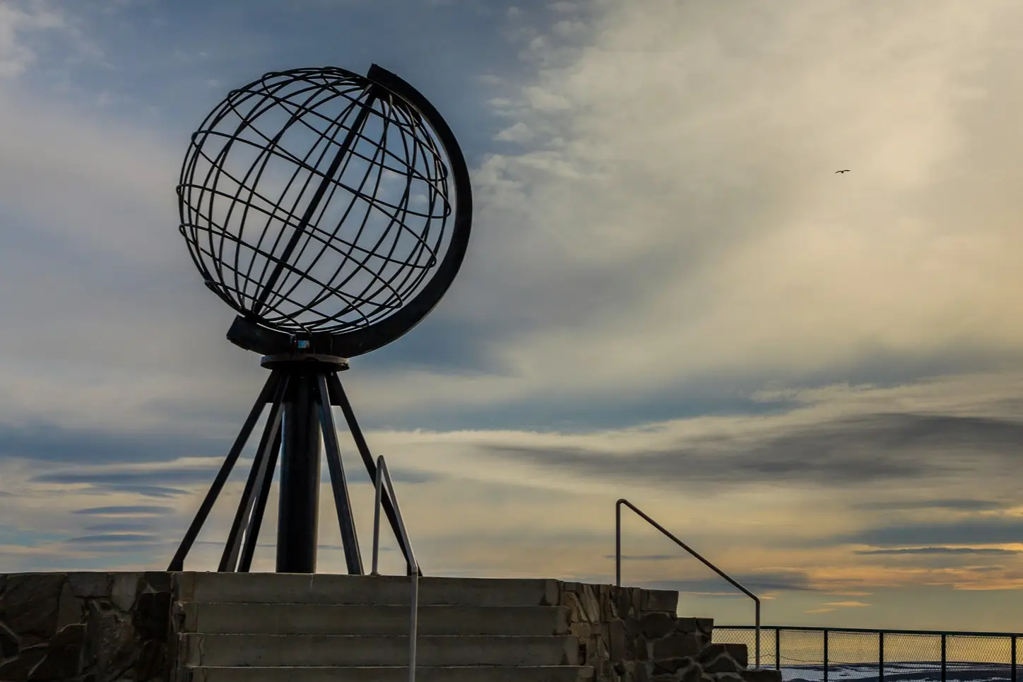Globe terrestre au point le plus au Nord de l'Europe, sous un ciel nuageux au coucher du soleil, Cap Nord, Norvège.