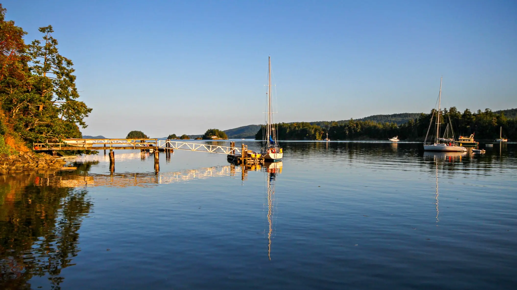 Voiliers et ponton dans une baie tranquille au coucher du soleil, Salt Spring Island, Colombie-Britannique, Canada.