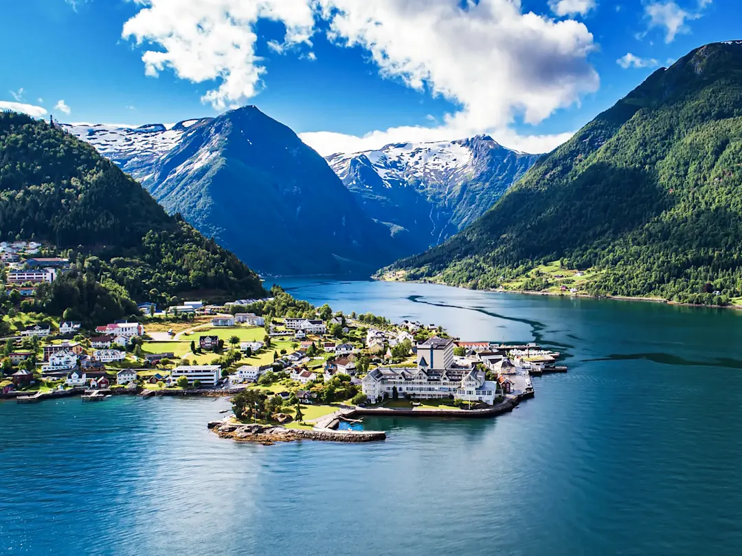 Eine kleine Stadt an einem ruhigen Fjord umgeben bewaldeten Bergen, Balestrand, Norwegen.