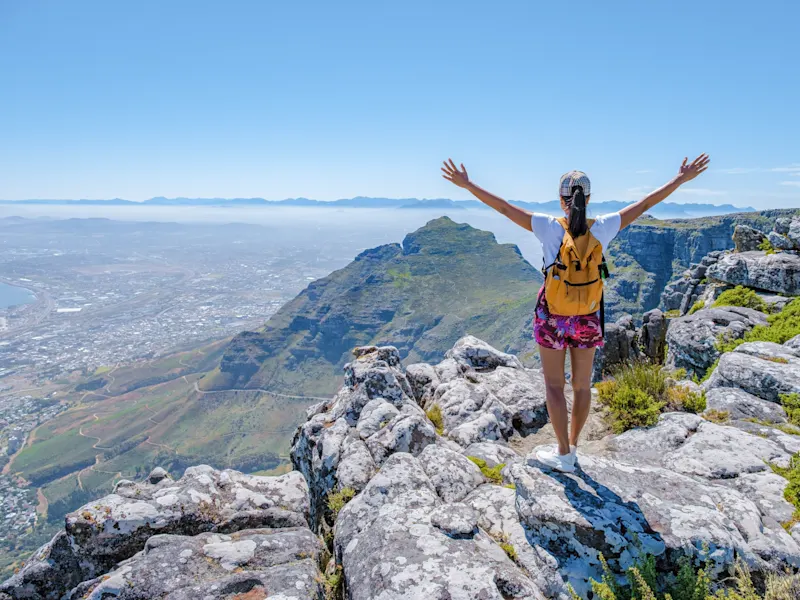 Kapstadt, Westkap, Südafrika. Frau auf Tafelberg mit Blick auf Stadt und Berge, Kapstadt, Westkap, Südafrika.