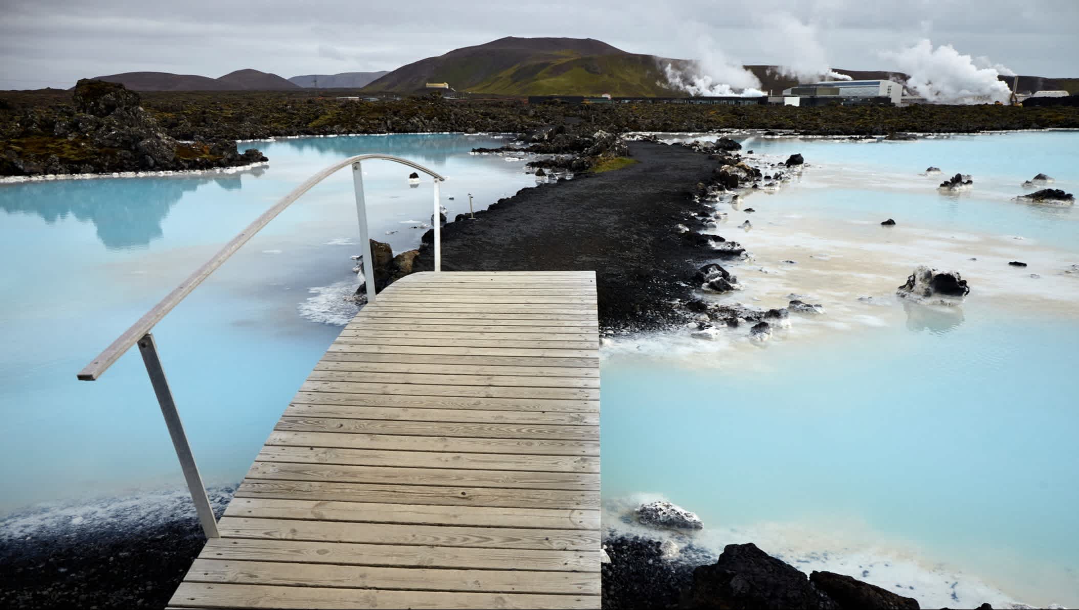 Holzbrücke an der Blauen Lagune mit felsiger und vulkanischer Landschaft in Island