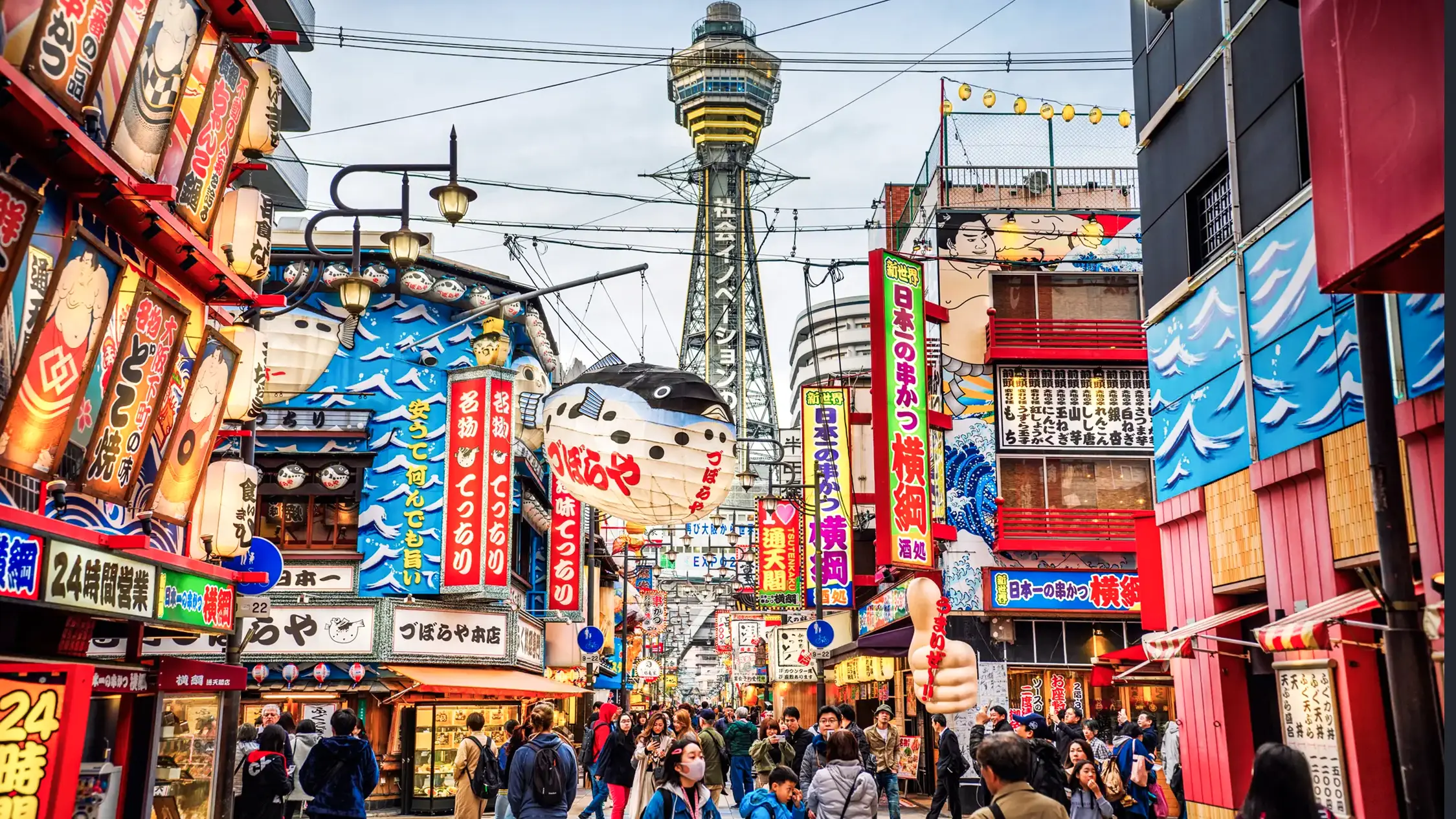 Japan, Kansai, Osaka Bunte Straßen mit Tsutenkaku-Turm im Hintergrund, Osaka, Kansai, Japan.