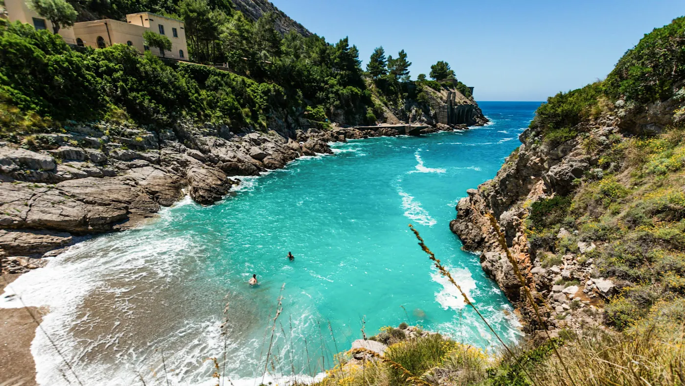 View of the small bay of Ieranto with turquoise blue sea and green rocky landscape
