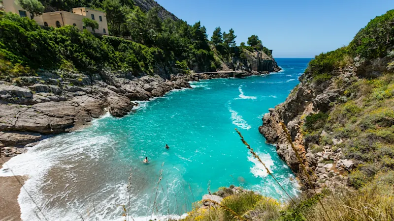 View of the small bay of Ieranto with turquoise blue sea and green rocky landscape