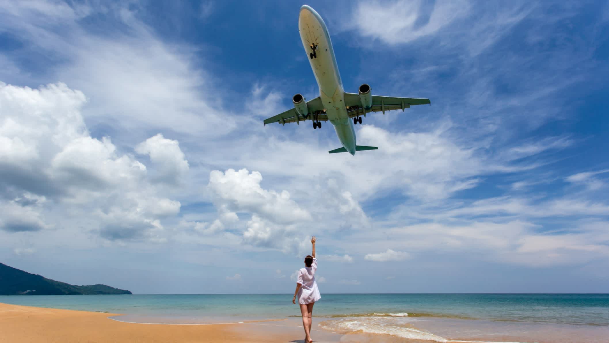 Une femme et un avion au-dessus de la plage de Mai Khao, Phuket, Thaïlande.