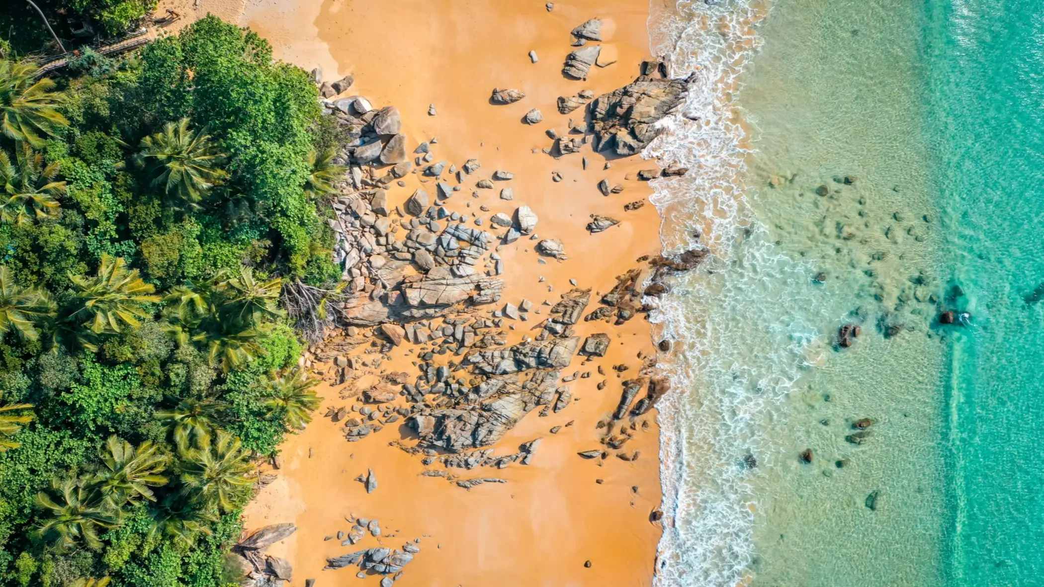 Thailand, Phuket, Nai Thon Beach Luftaufnahme des Nai Thon Beach mit tropischen Bäumen, goldgelbem Sand, Felsen und türkisblauem Wasser.