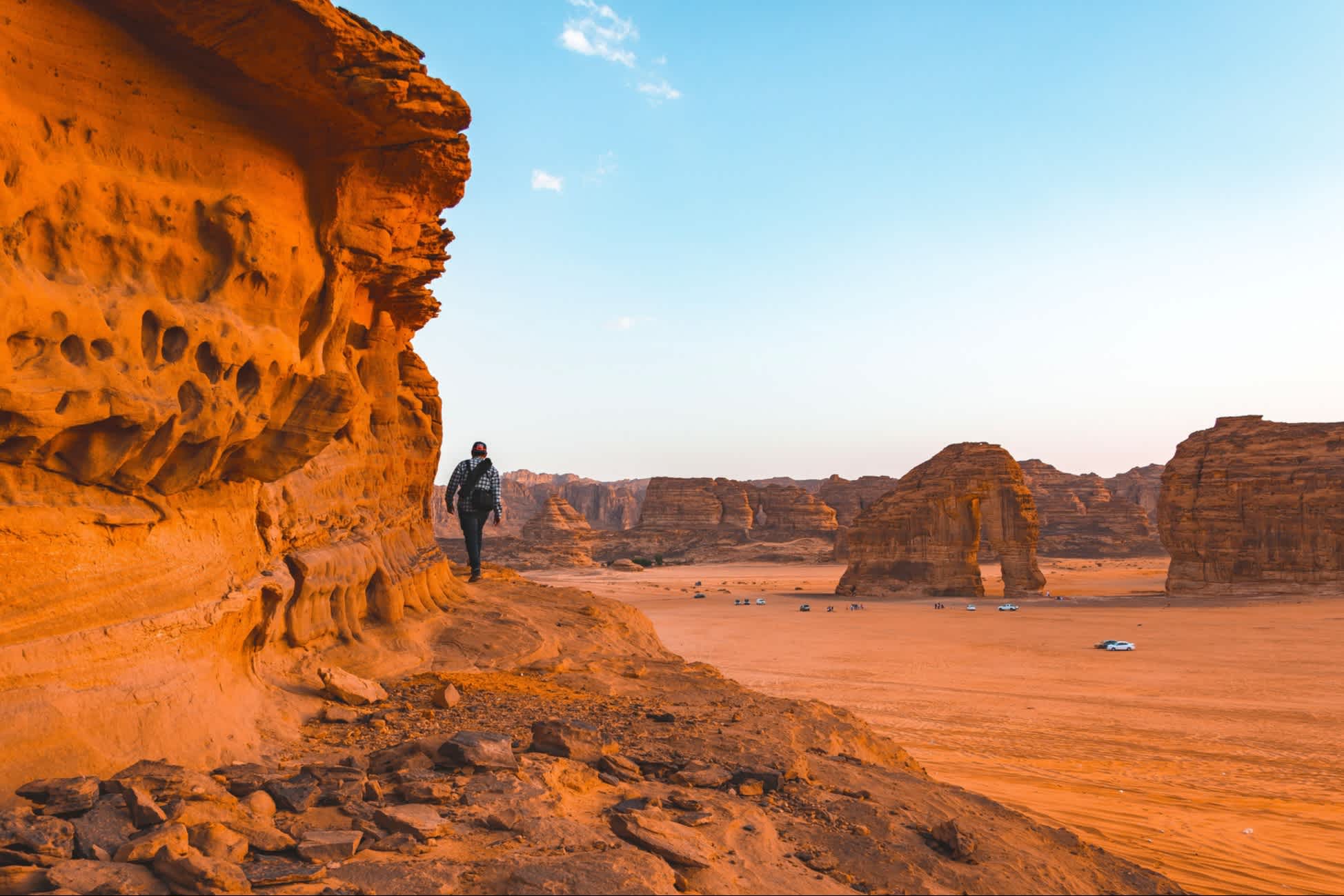 Ein Mann der an einem großen Felsen in einer Wüste entlang wandert