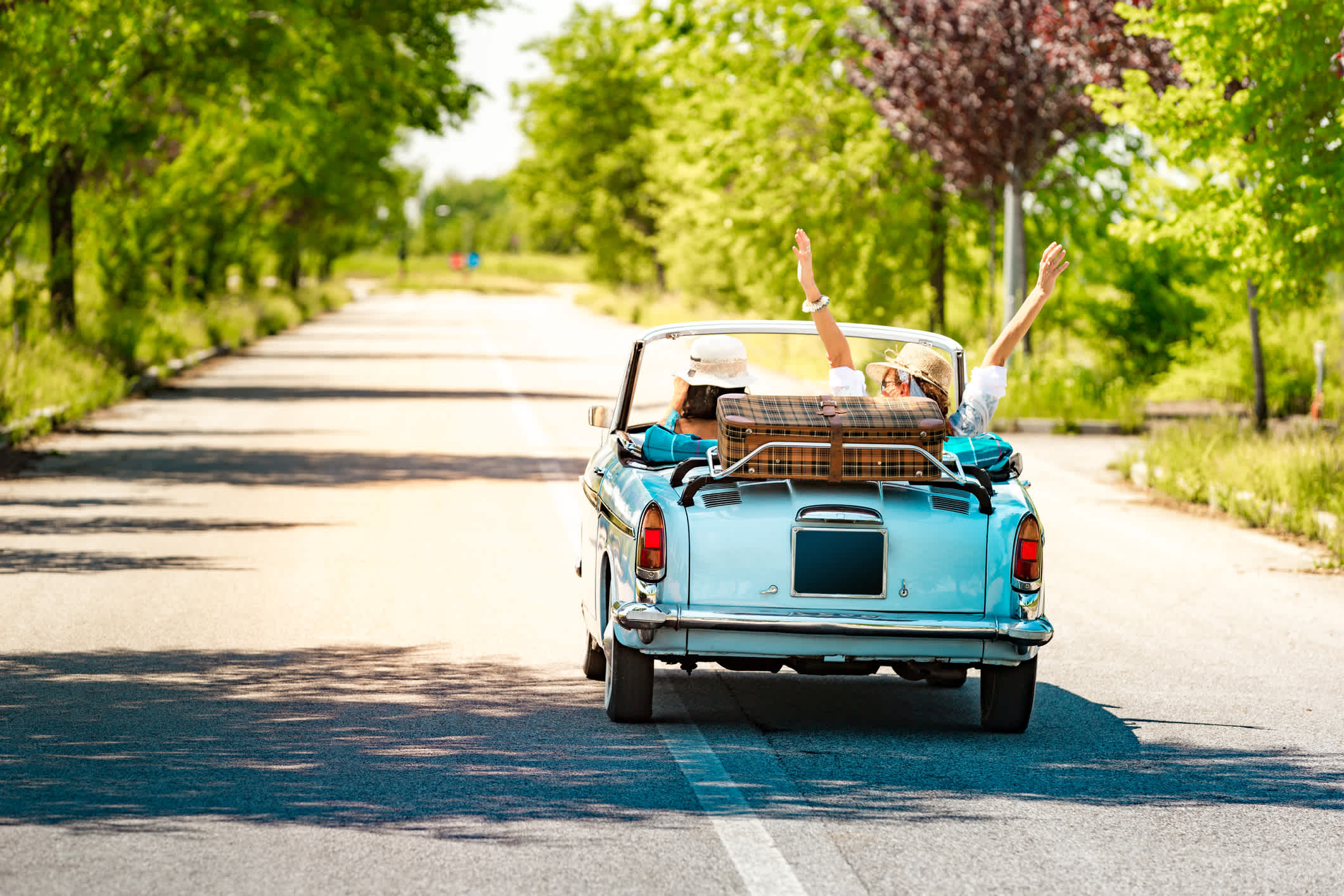 Un couple dans une voiture décapotable de collection, lors d'un road trip en Italie.