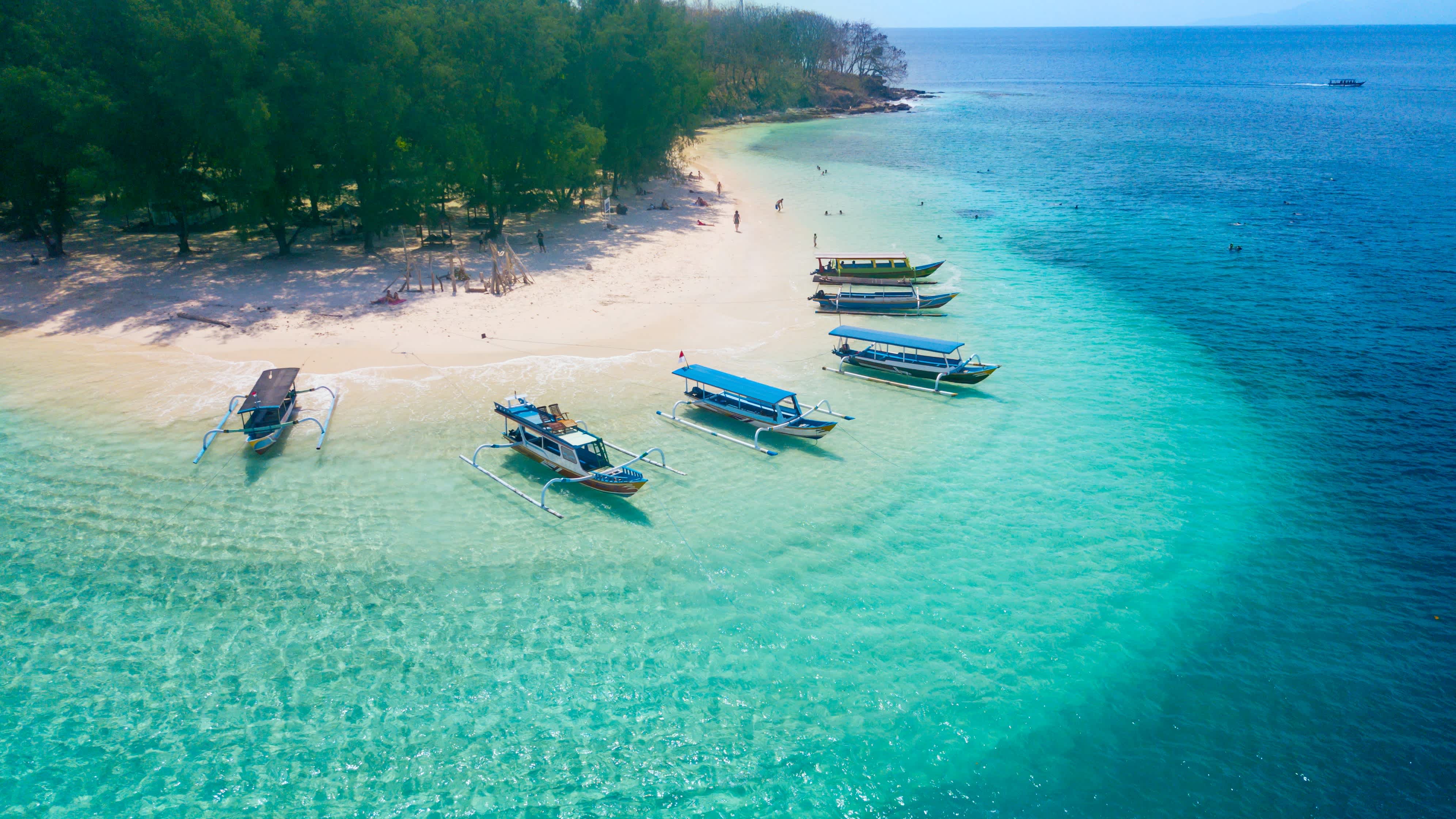 Bateaux au bord de la plage de sable blanc et de l'eau turquoise, îles Gili, Lombok, Indonésie