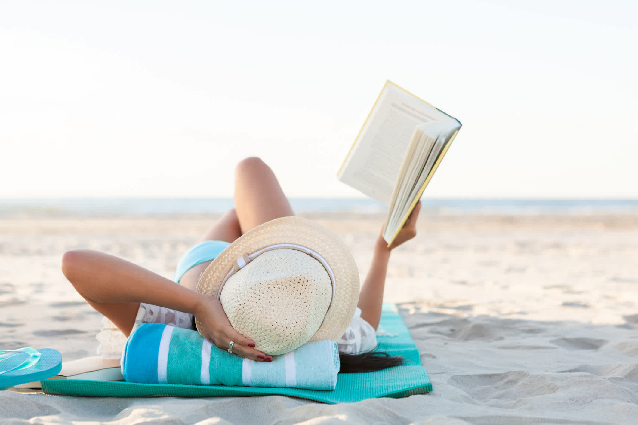 Frau liest Buch beim Sonnenbaden am Strand 