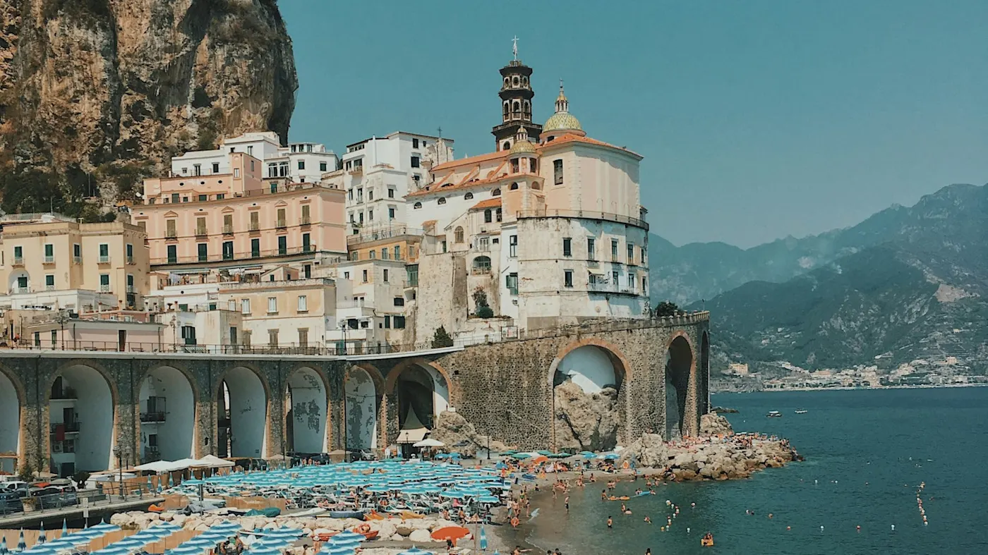 Beach with colorful umbrellas and coastal town. Amalfi, Campania, Italy