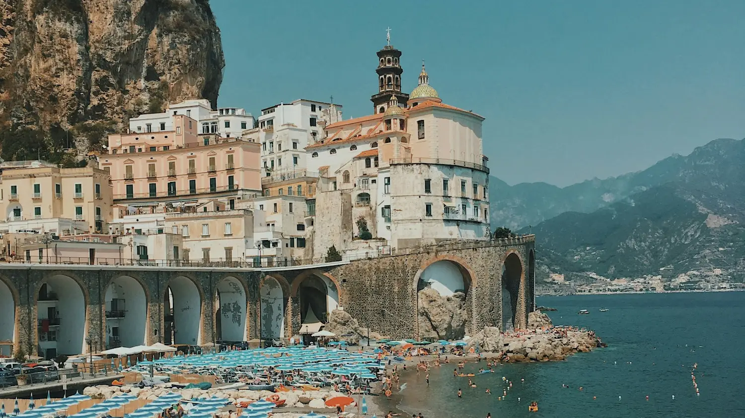 Italy, Campania, Amalfi Beach with colorful umbrellas and coastal town. Amalfi, Campania, Italy