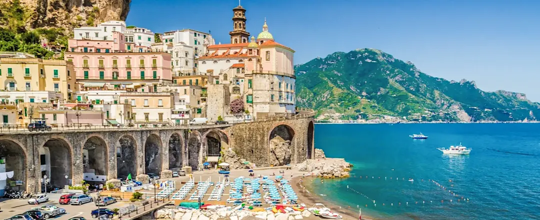 Strand mit bunten Schirmen und Küstenstadt. Amalfi, Kampanien, Italien