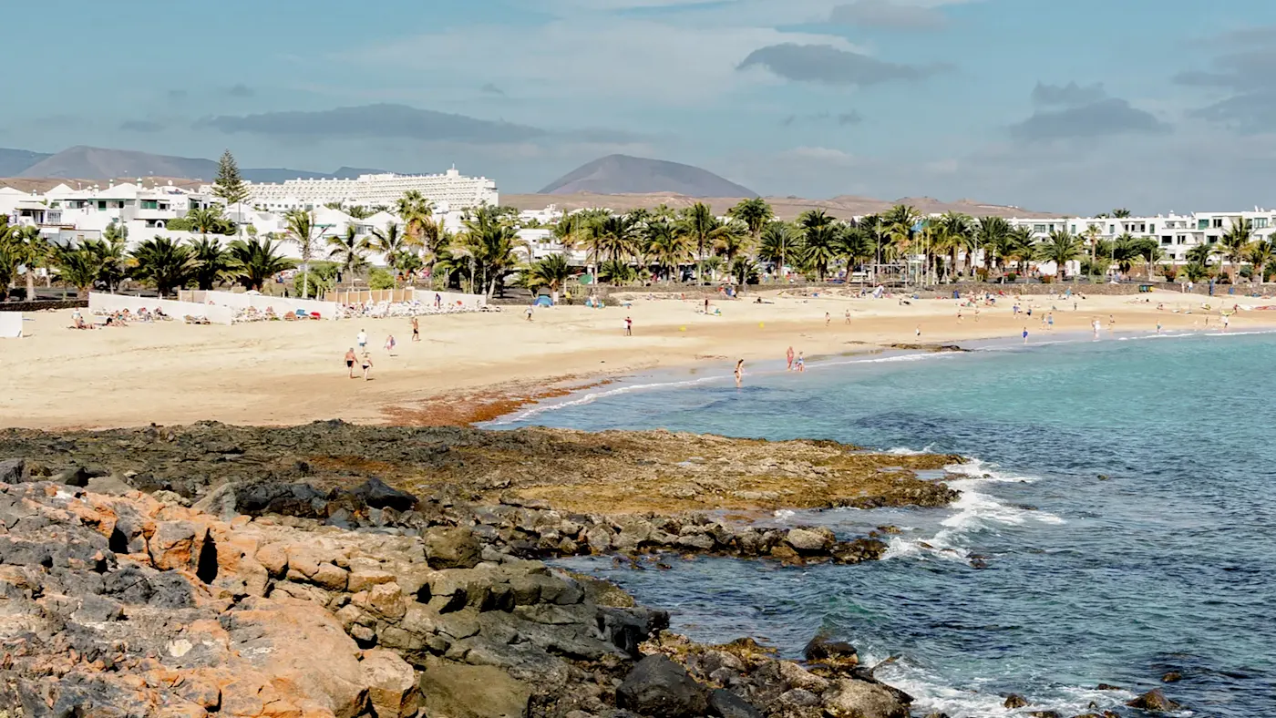 Strand mit Palmen und türkisfarbenem Meer. Costa Teguise, Lanzarote, Kanarische Inseln, Spanien.