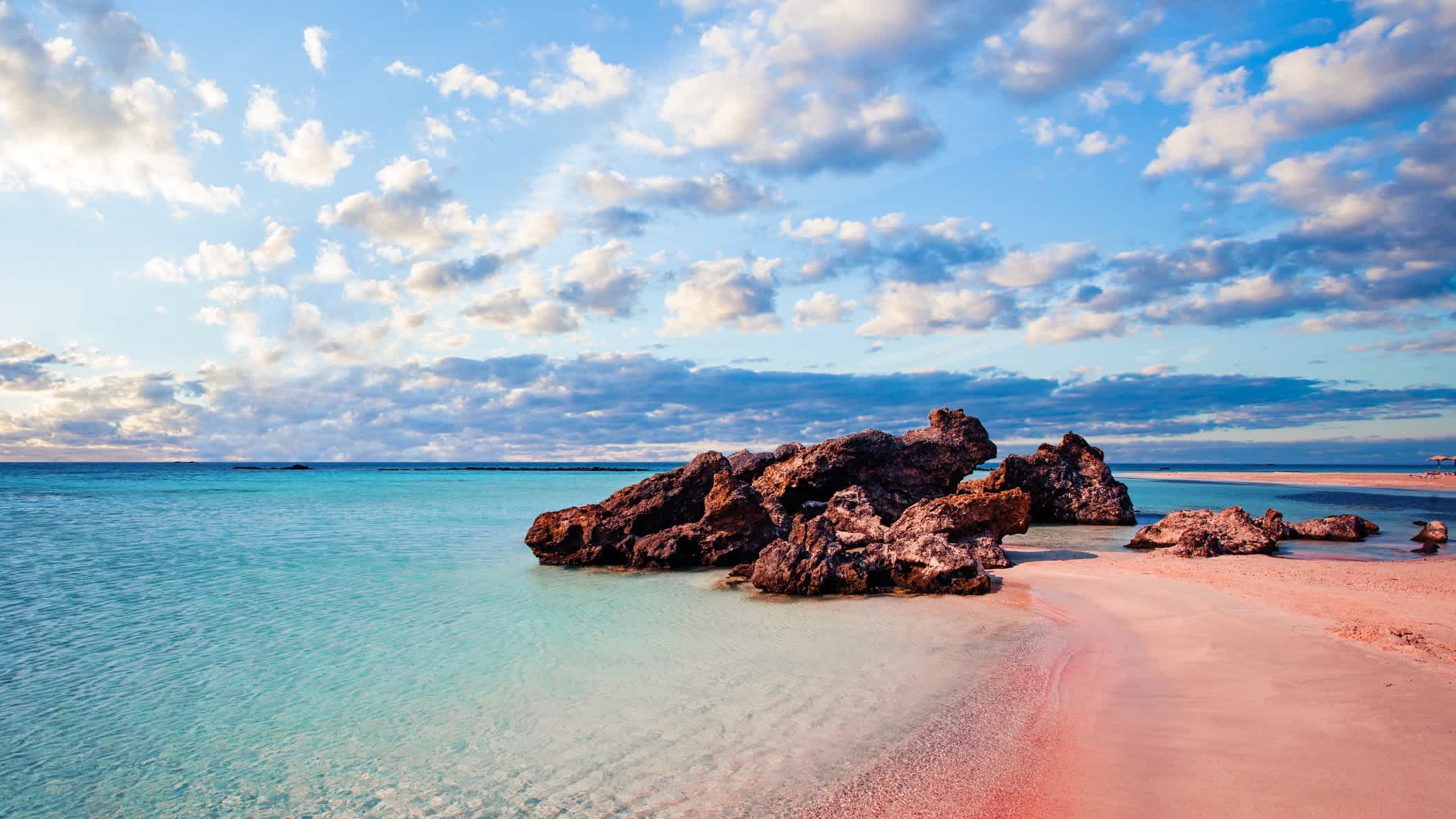 Elafonissi Strand mit rosa Sand auf Kreta, Griechenland bei Sonnenschein und Wolken am Himmel.