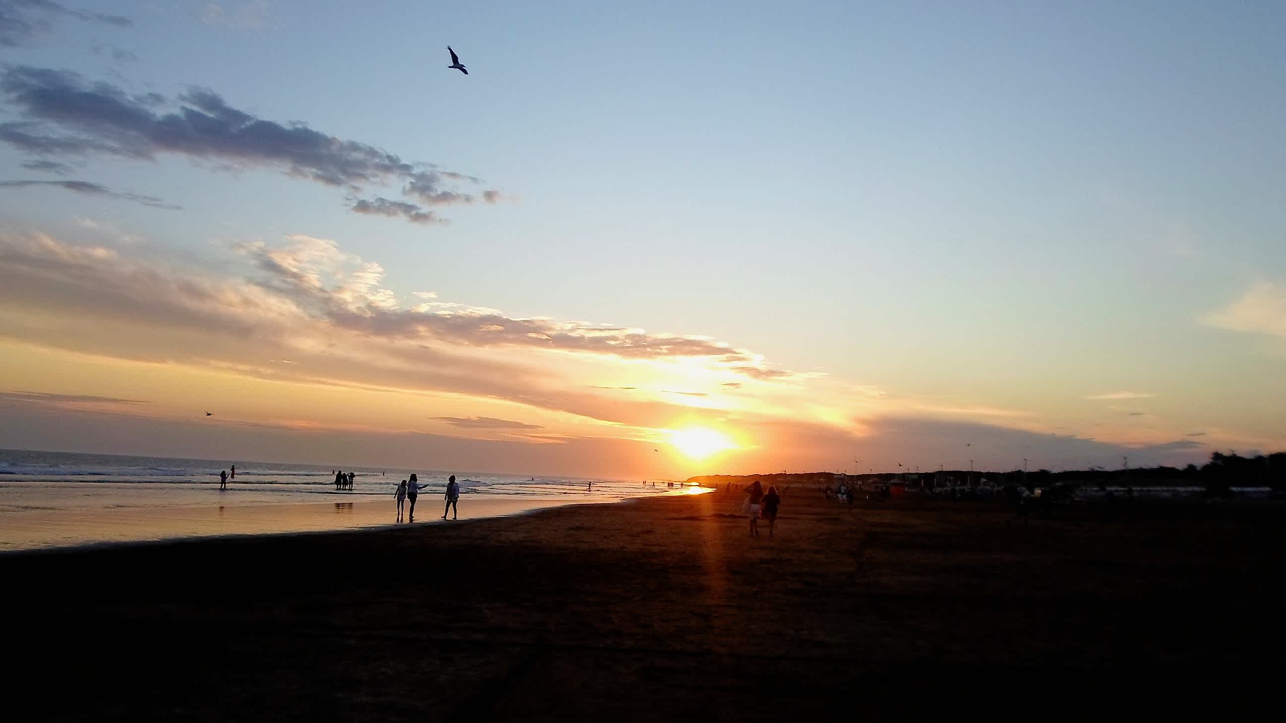 Personnes marchant au bord de la plage de Necochea en Argentine, au coucher du soleil