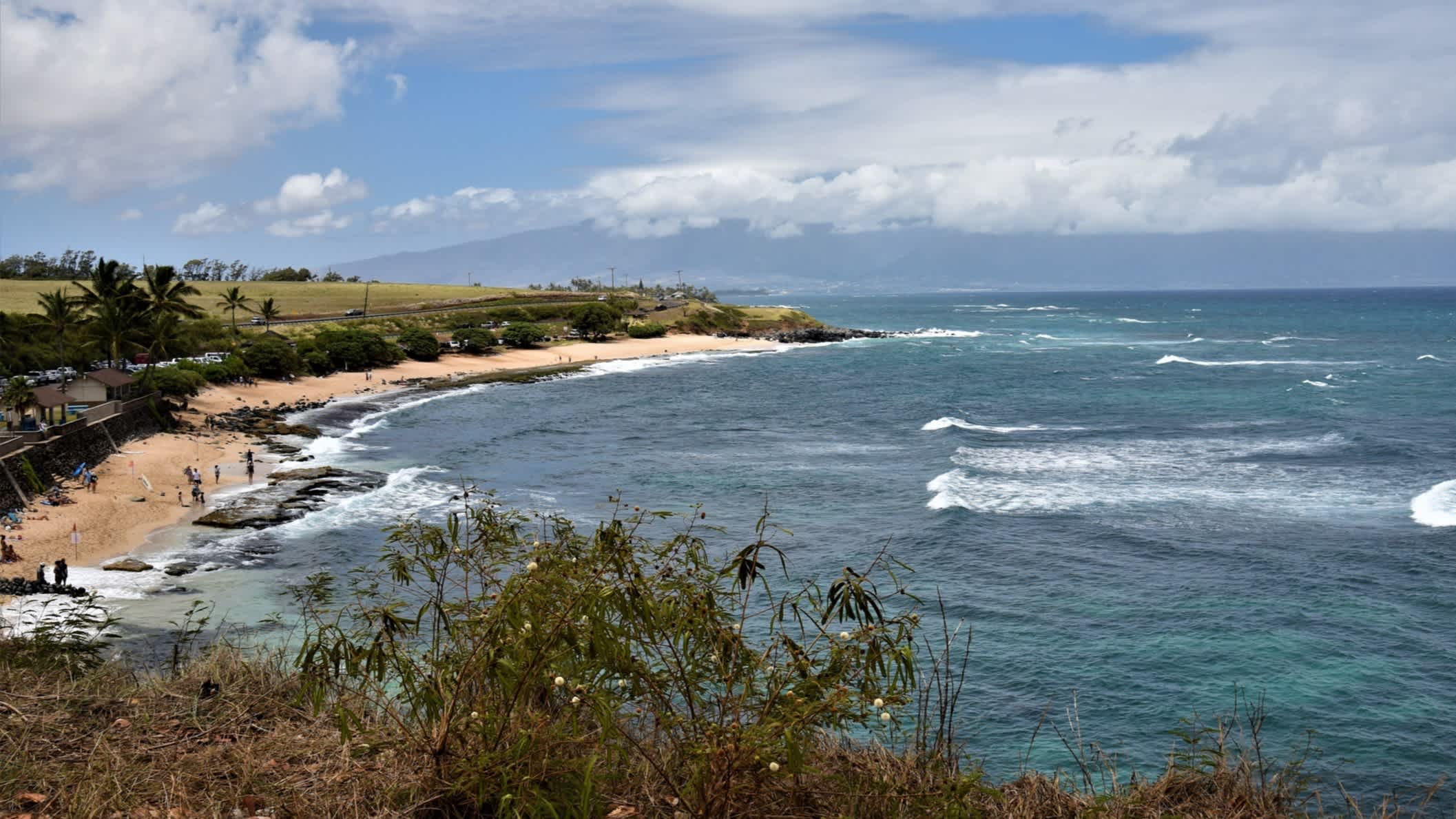 Der Strand Hookipa-Strand, Maui, Hawaii, USA bei Sonnenschein und mit Blick auf das wellige Meer sowie die Küste von einem Viewpoint aus.
