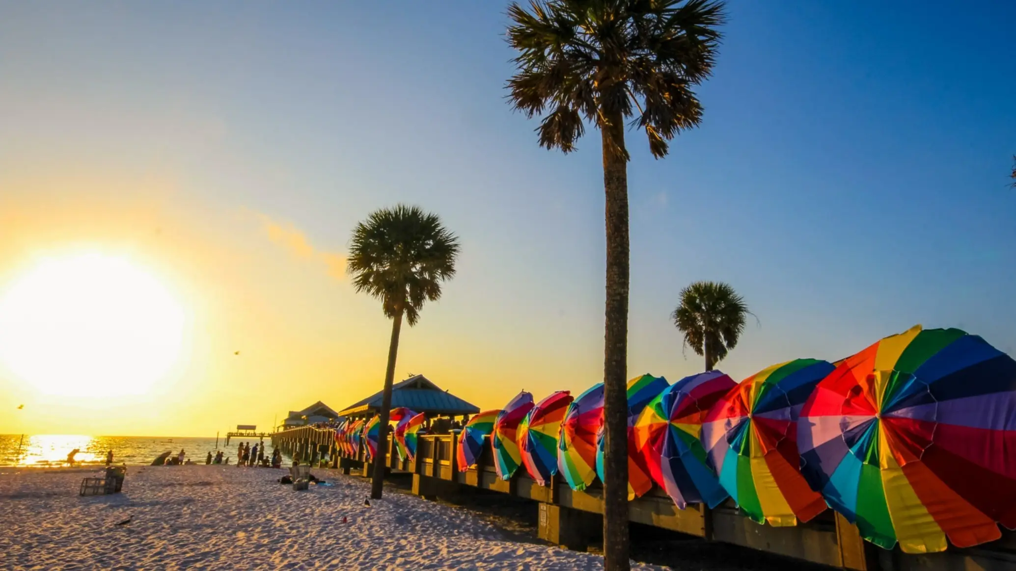 USA Florida Clearwater Beach Der Strand Clearwater Beach, Clearwater, Florida, USA bei Sonnenuntergang mit Blick auf bunte Sonnenschirme, Palmen und das Meer.