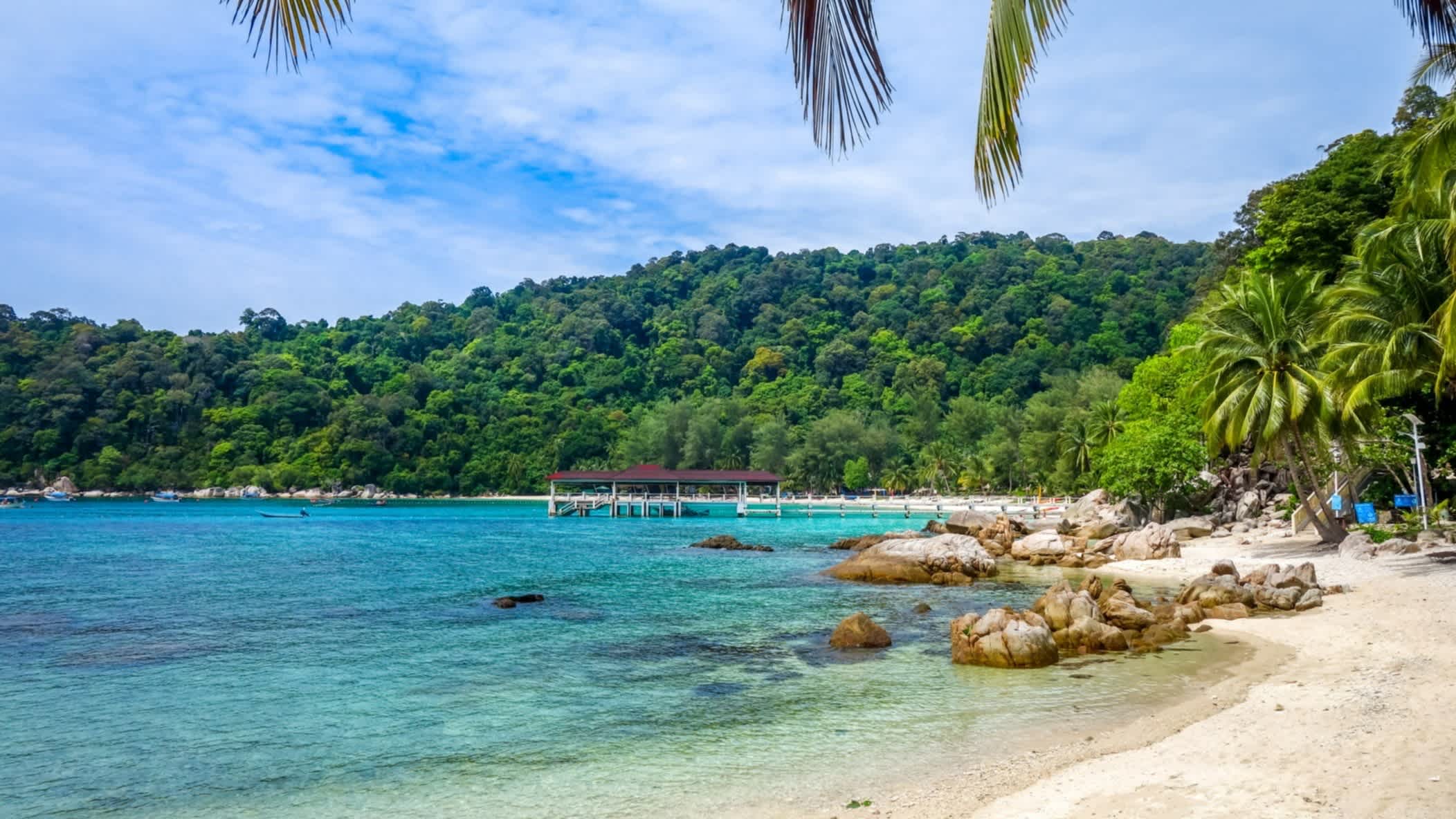 Blaues Meer am Naturstrand Teluk Pauh Beach, Perhentian Islands, Terengganu, Malaysia mit Blick auf die tropische Umgebung und einen Steg im Wasser.