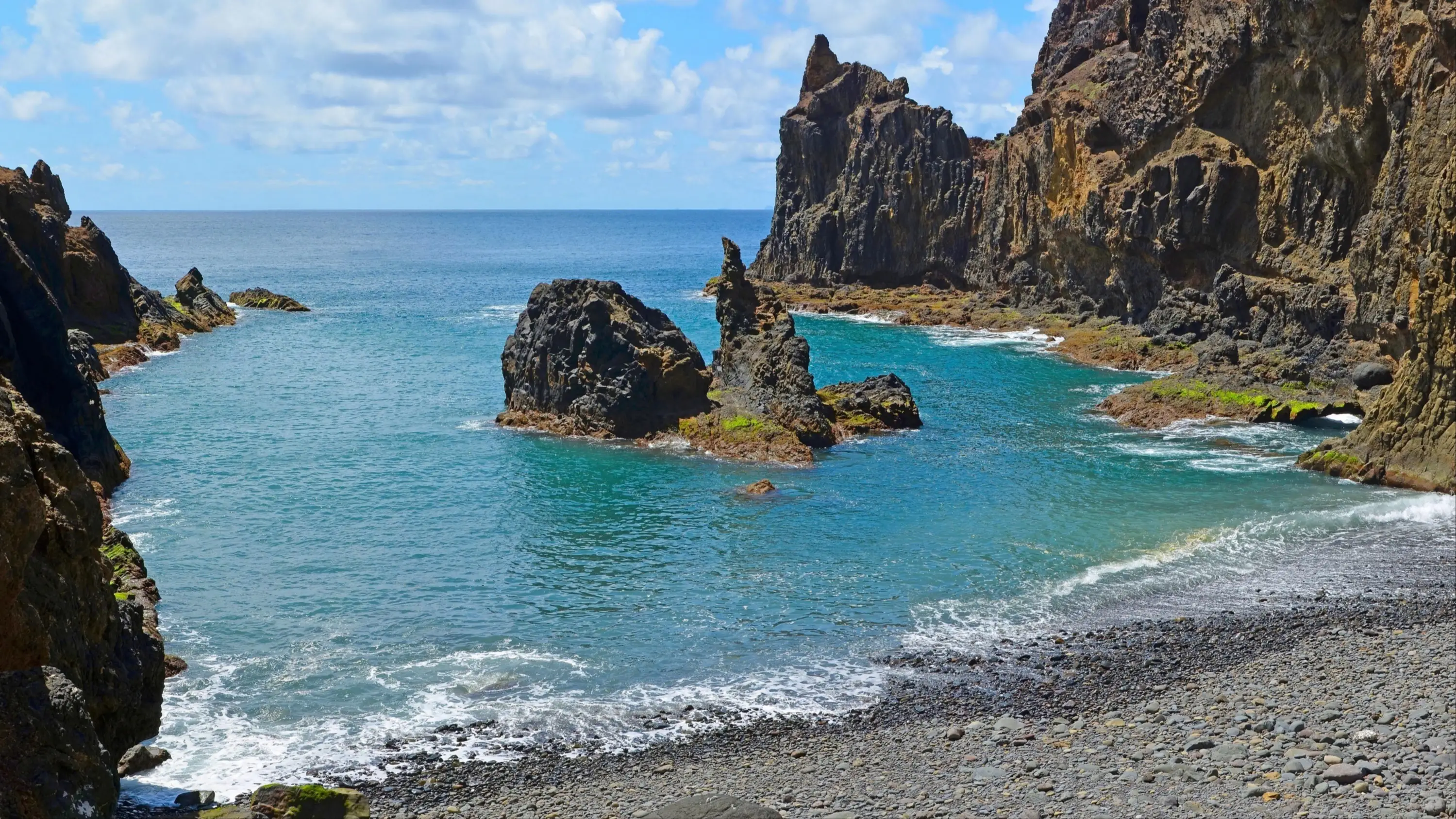 Praia Porto Santo, Porto Santo, Madeira, Portugal Kleiner grauer Kieselstrand umgeben von Felsen am Praia Porto Santo, Porto Santo, Madeira, Portugal.