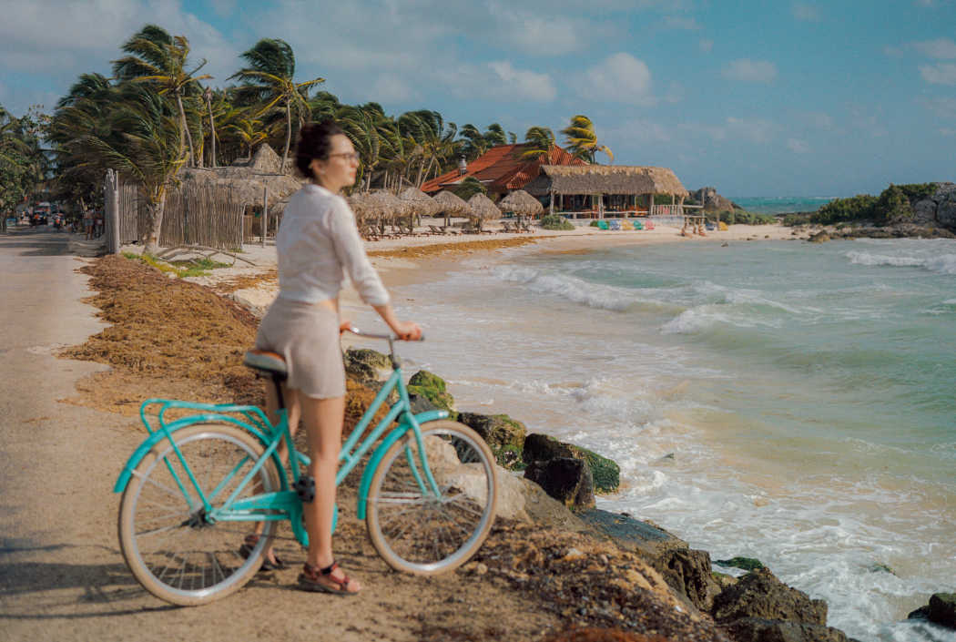 Frau auf dem Fahrrad am Strand in Tulum, Mexiko. 