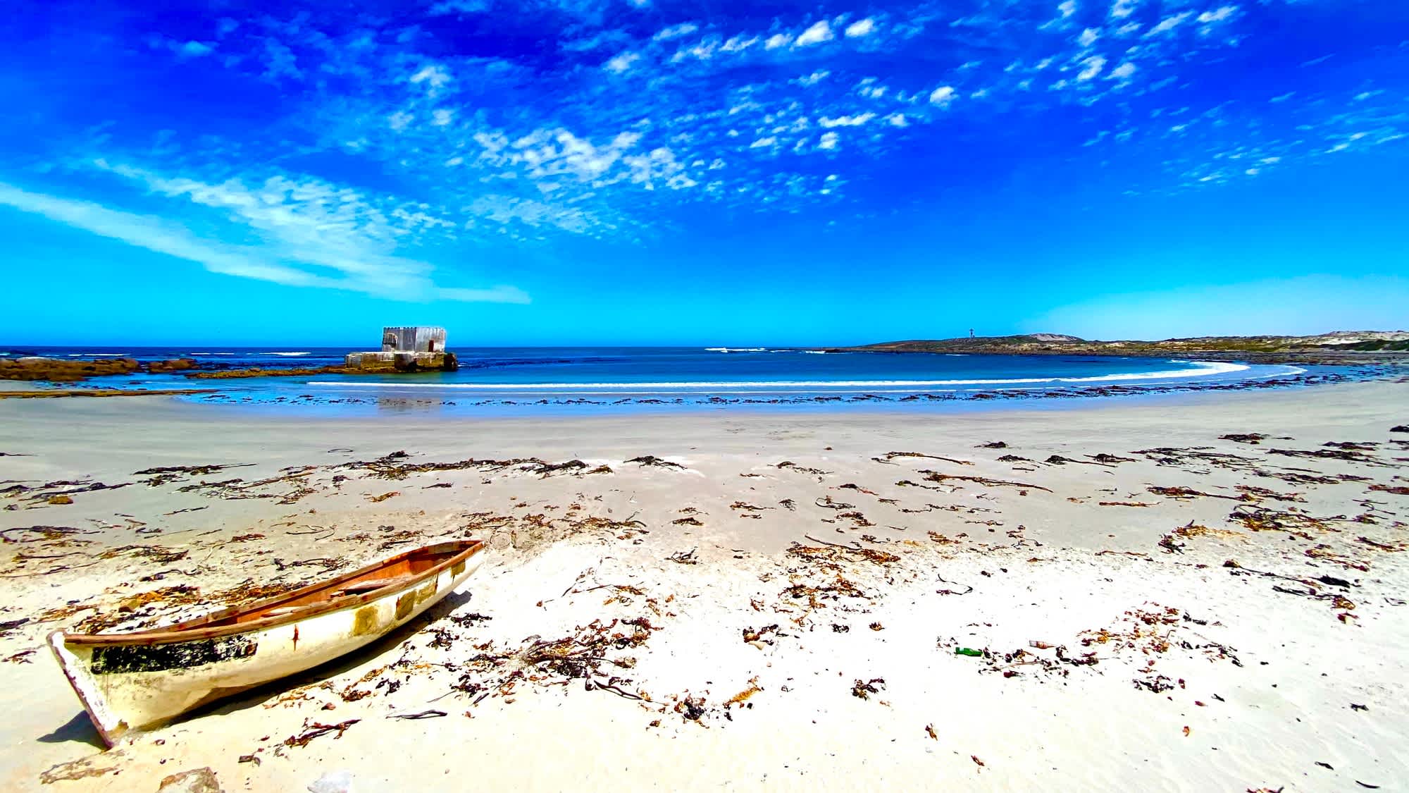 Ein Blick auf den wunderschönen weißen Sandstrand der Leisure Bay in Südafrikas KwaZulu-Natal Region mit Booten bei Ebbe.