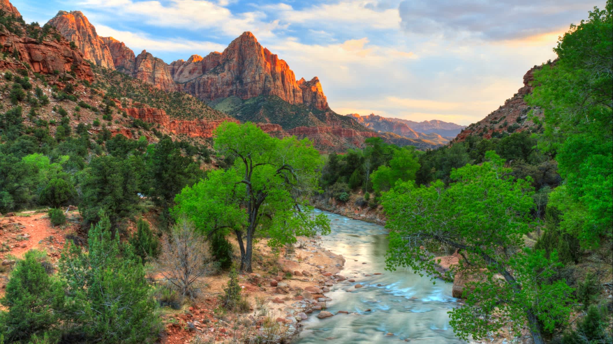 Bild der letzten Sonnenstrahlen, die auf den Watchman treffen, mit dem Virgin River im Vordergrund im Zion National Park, Utah, USA.