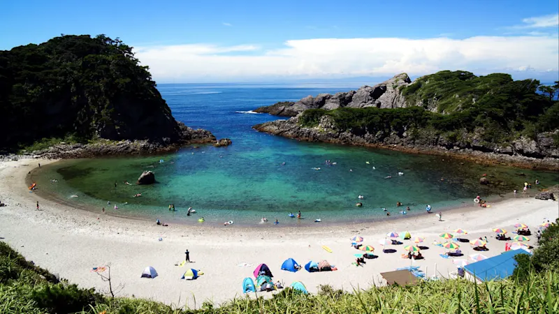 Shikinejima, Niijima-mura, Japan Blick auf die kleine Bucht von Shikinejima, Niijima-mura, Japan mit türkisblauem Wasser und Felsen.