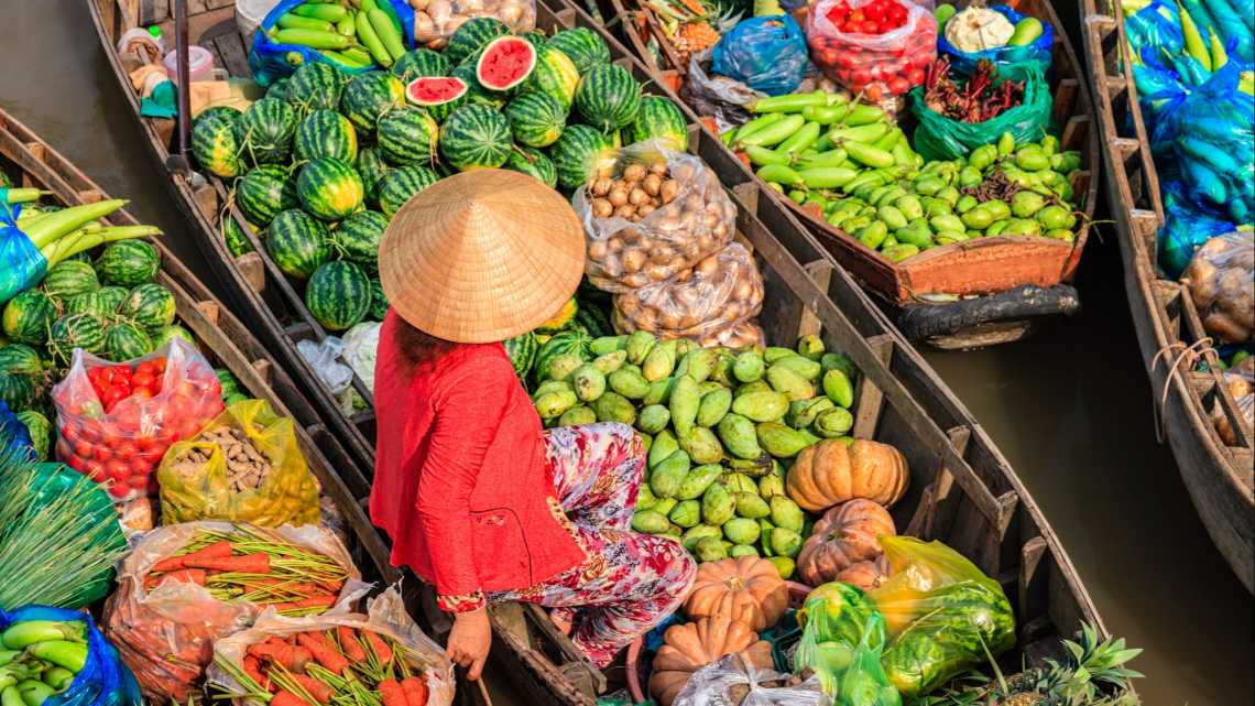 Vietnamesische Frau verkauft Früchte auf einem schwimmenden Markt im Mekong-Delta, Vietnam