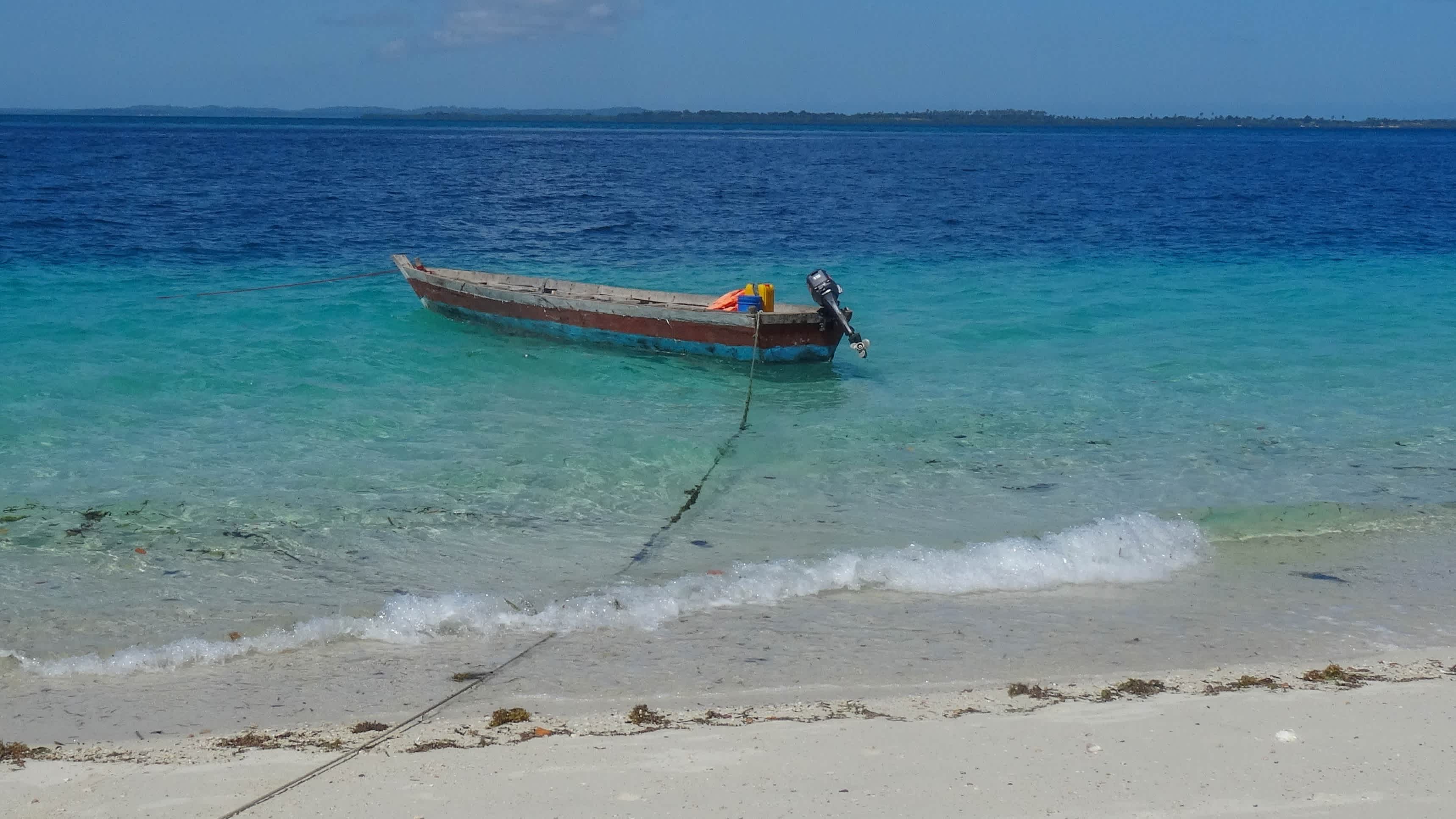 Ein traditionelles Holzboot ankert im kristallklaren Wasser und bei Sonnenschein vor der Insel Misali, Tansania.
