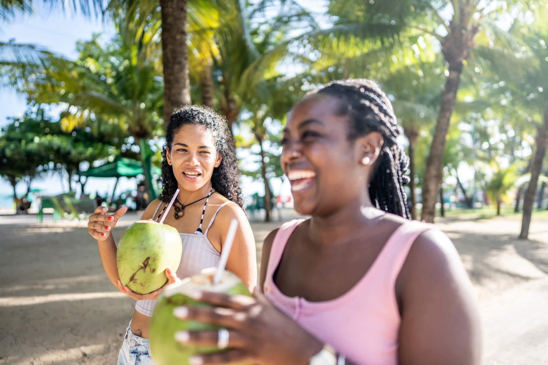 Freunde, die auf einer Promenade spazieren gehen und Kokoswasser trinken