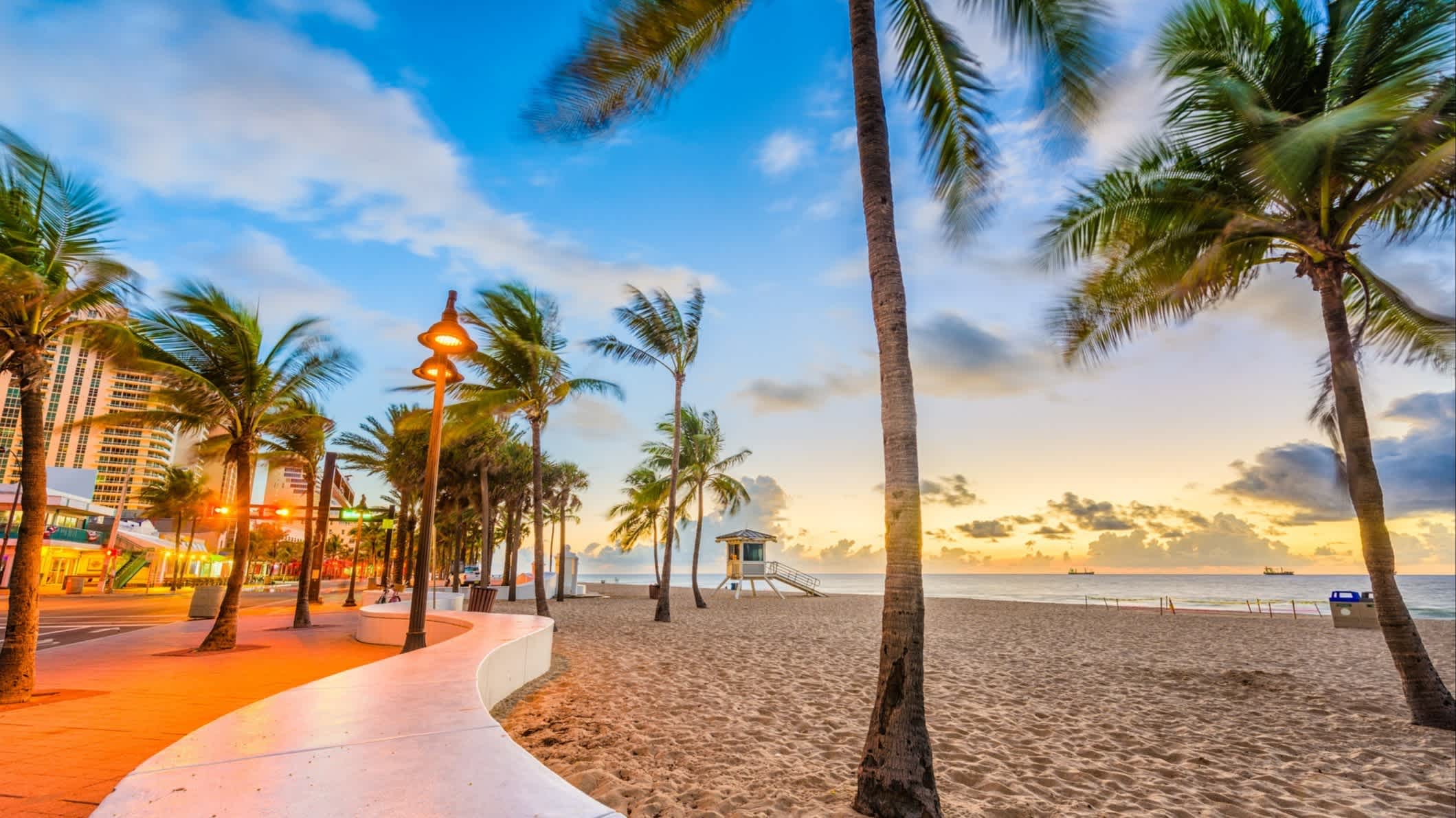 Der Strand von Fort Lauderdale Beach, Fort Lauderdale, Florida, USA bei purem Sonnenschein mit Blick auf die belebte Promenade und Palmen. 