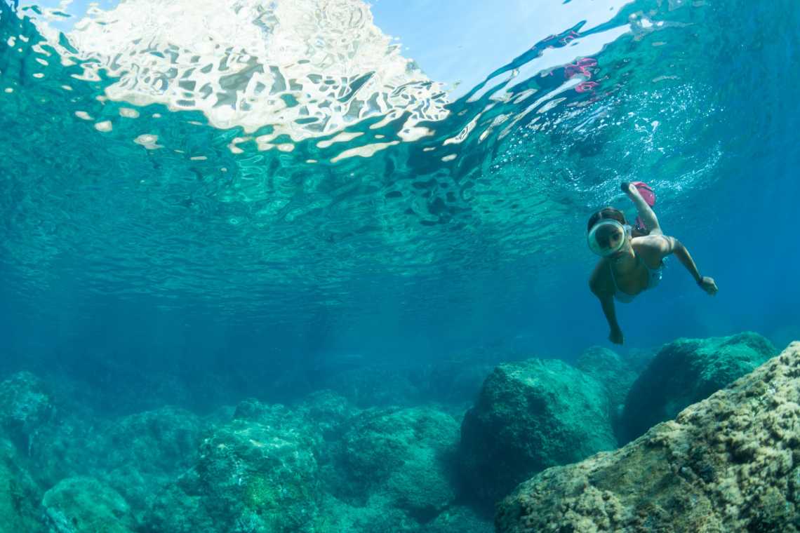 Eine Frau taucht unter einem klaren Wasser. 