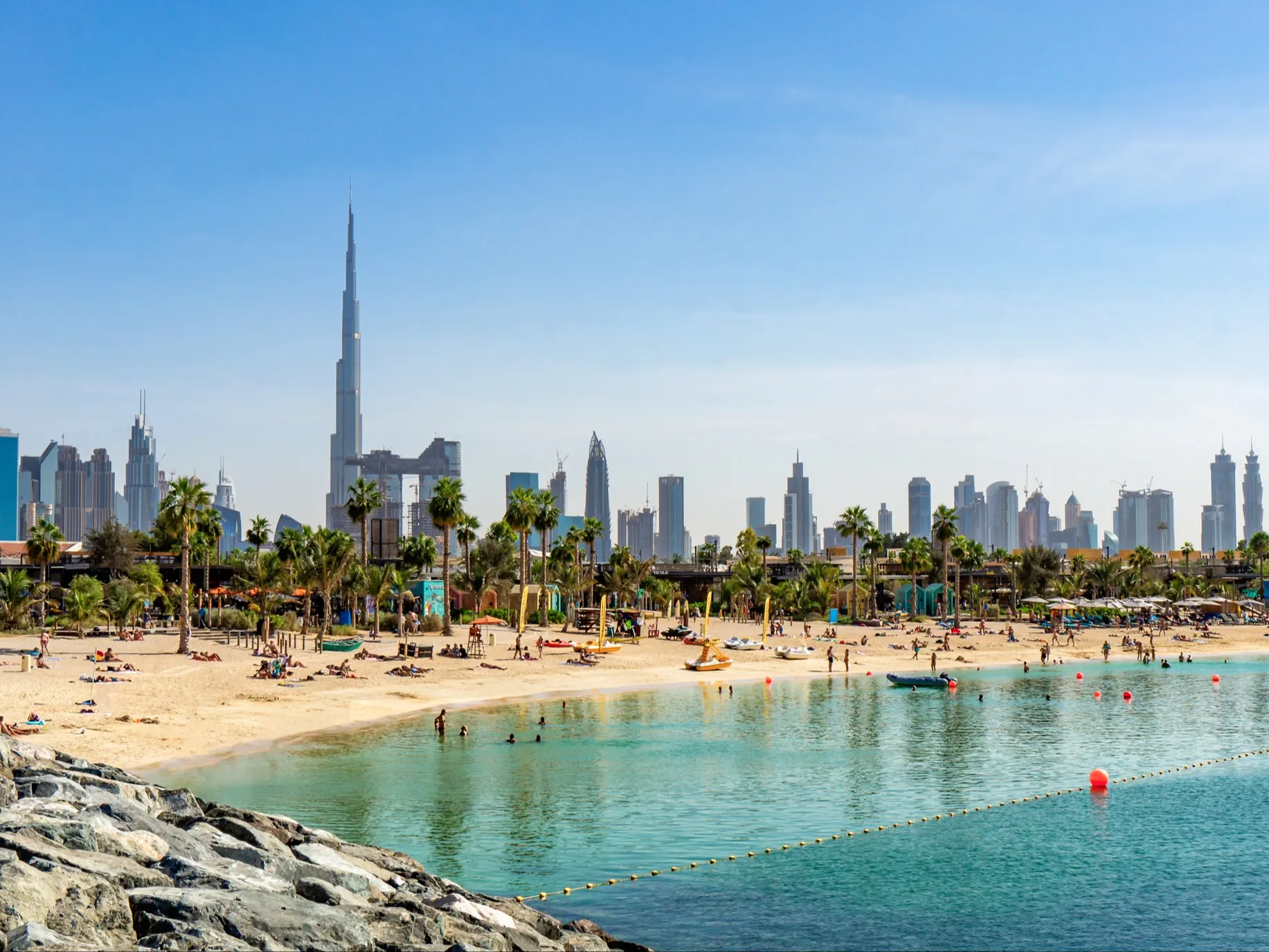 Blick auf den Strand in Dubai mit Wolkenkratzern und dem höchsten Turm der Welt Burj Khalifa im Hintergrund, VAE.