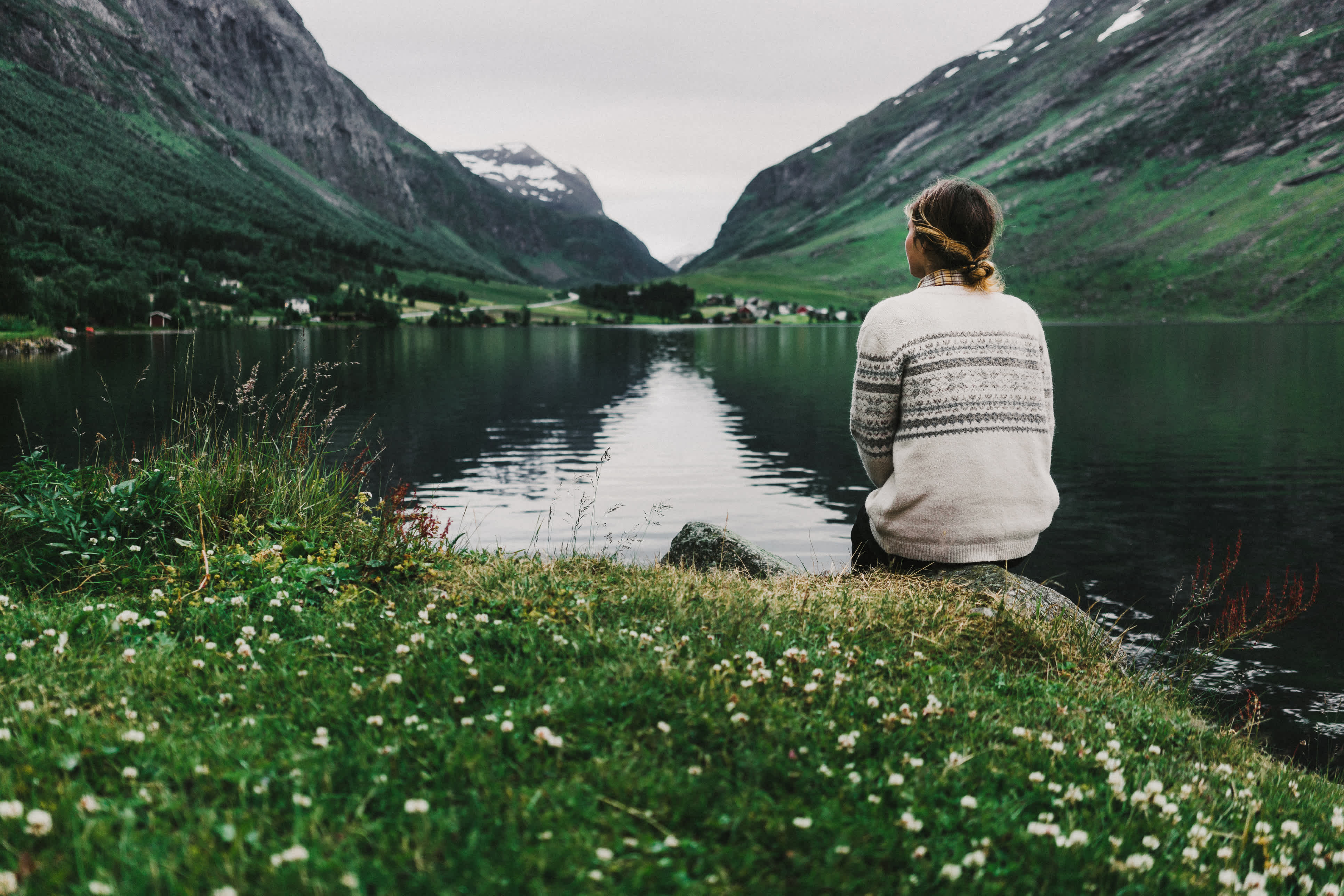 Femme pendant un voyage solo assise au bord d'un lac en Norvège. Étude Tourlane - Ifop sur le voyage solo et les femmes.