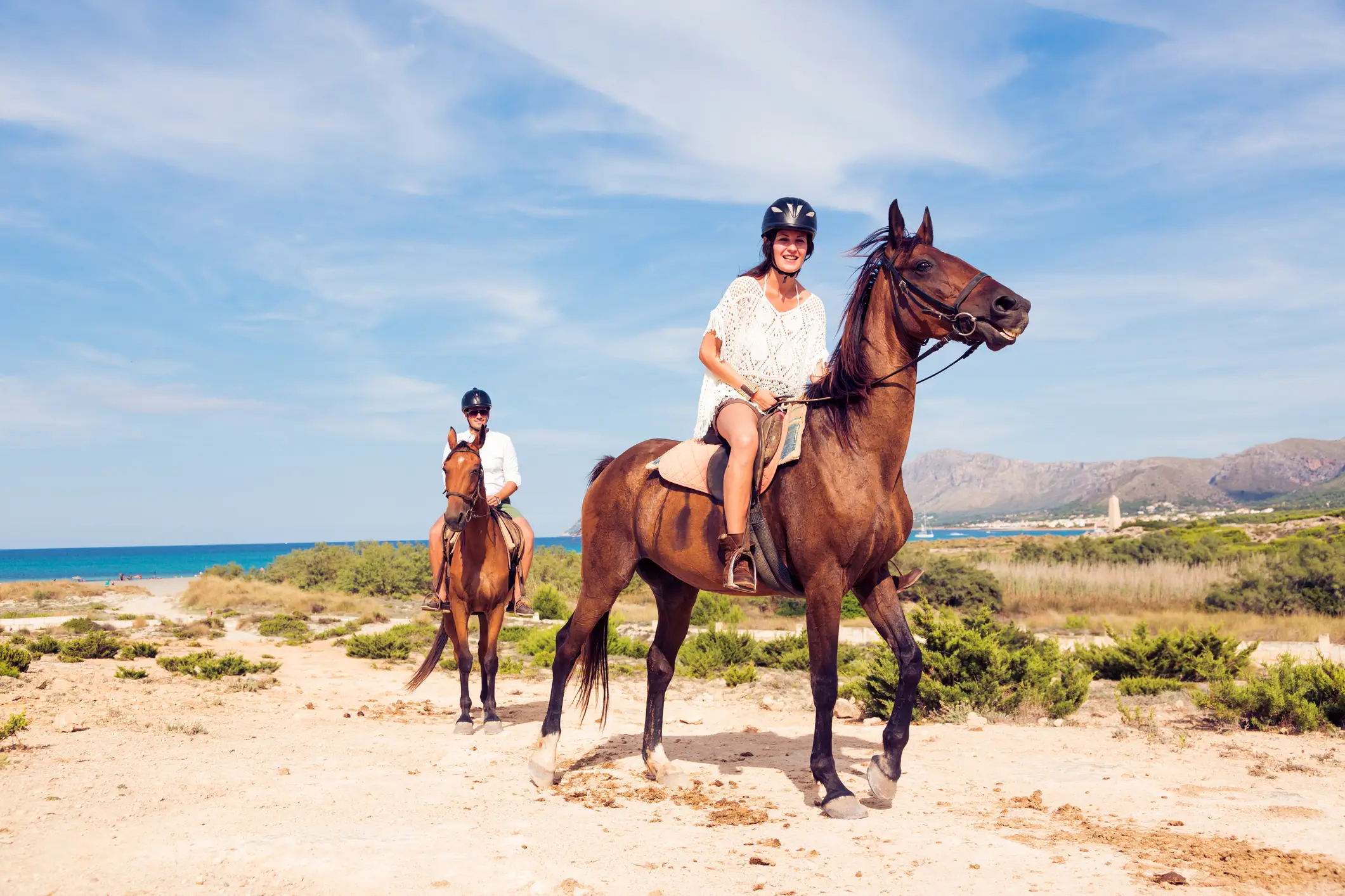 Couple de jeunes touristes à cheval sur la plage.