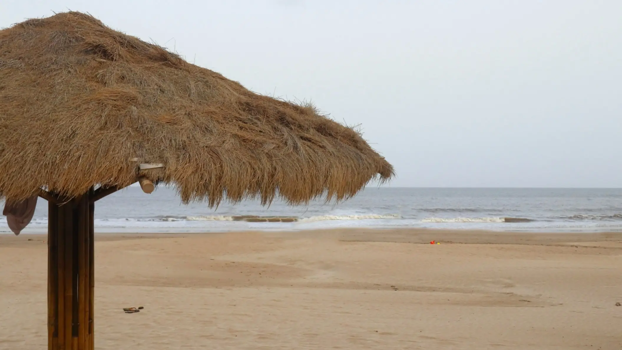 Ghoghla Strand, Gujarat, Indien Strohschirm am Ghoghla Strand, Gujarat, Indien bei bewölktem Wetter.