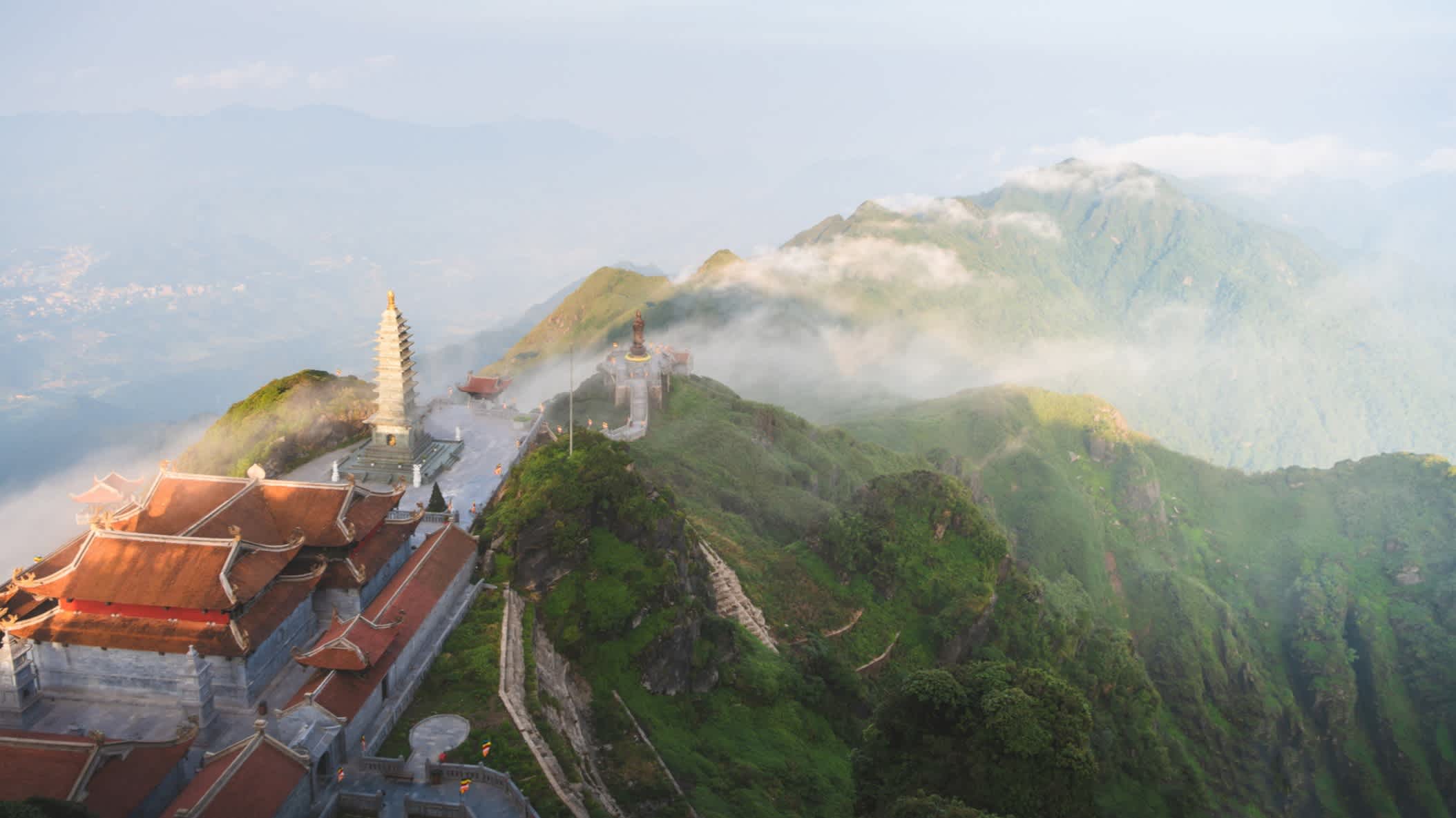 Neblige weite Landschaft des Fansipan-Bergs mit einem buddhistischen Tempel, Vietnam.