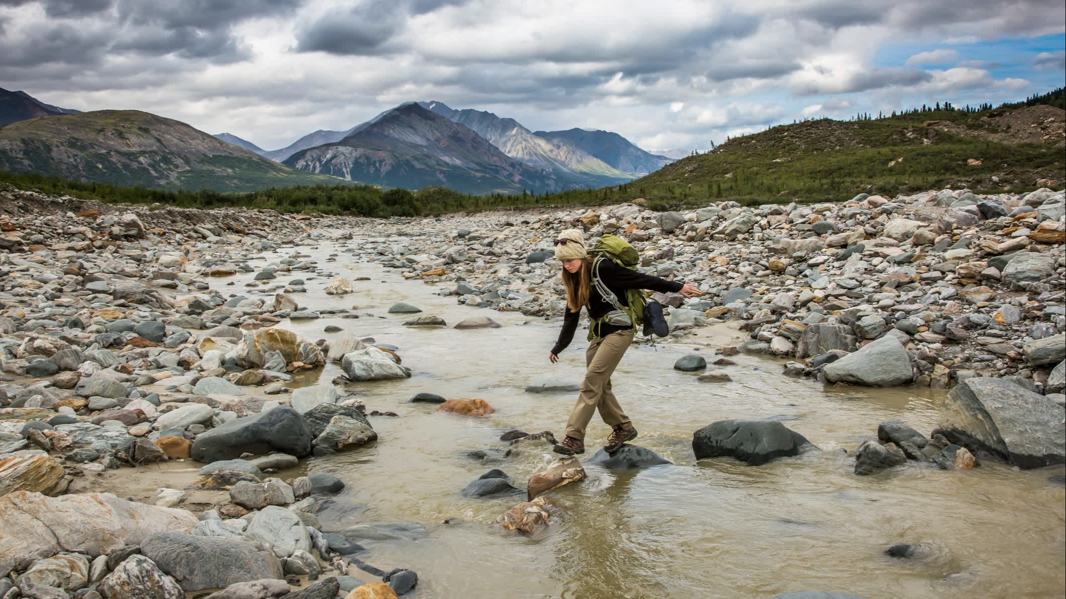 Une routarde traverse une rivière dans une région montagneuse isolée, Alaska, USA