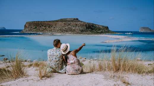 Un couple assis sur la plage face à la vue idyllique sur la plage de Balos en Crète, Grèce.
