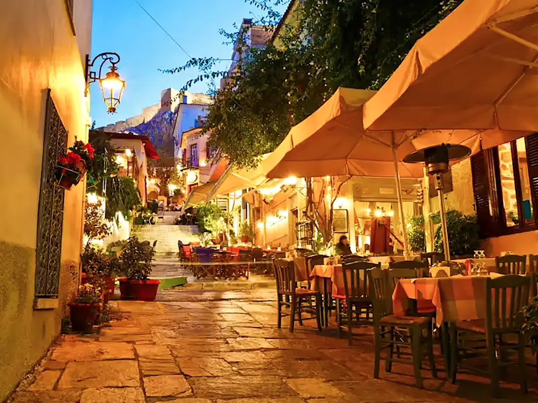 Eine charmante, beleuchtete Gasse mit Restaurants in Plaka, Athen, Griechenland.