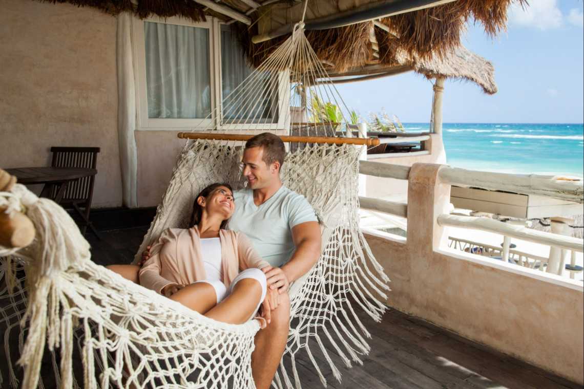 Un couple installé dans un hamac sur une plage de sable blanc, lors de leur voyage de noces au Mexique.