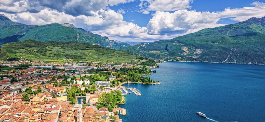 Stadt mit roten Dächern und Blick auf einen See umgeben von Bergen. Riva del Garda, Trentino, Italien